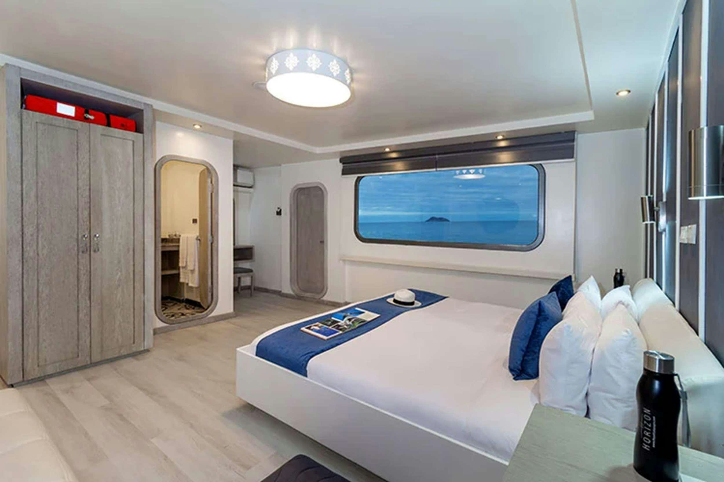 a room with a bed and a bottle of wine aboard GALAPAGOS HORIZON Yacht for Charter