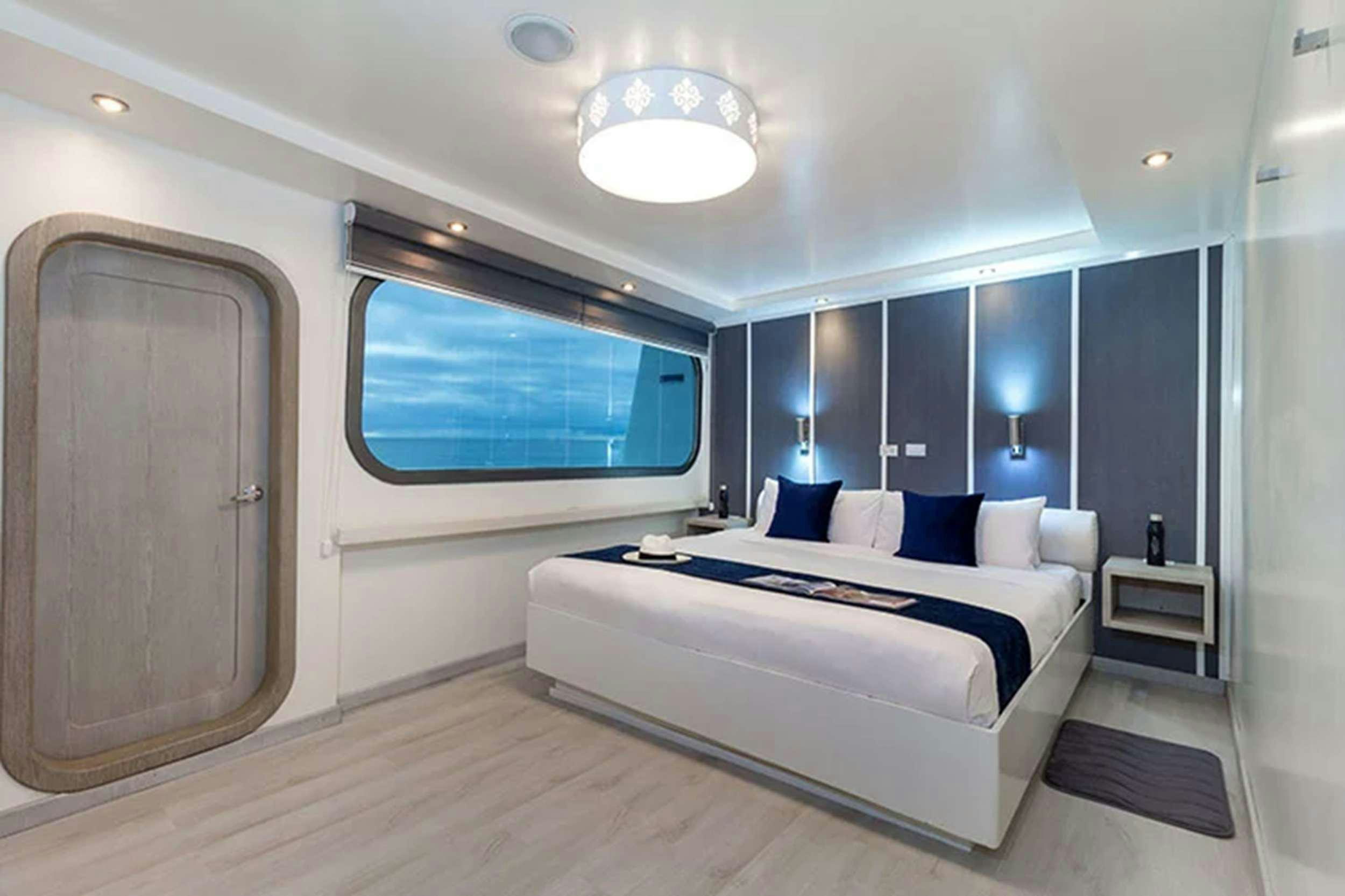 a room with a bed and a window aboard GALAPAGOS HORIZON Yacht for Charter