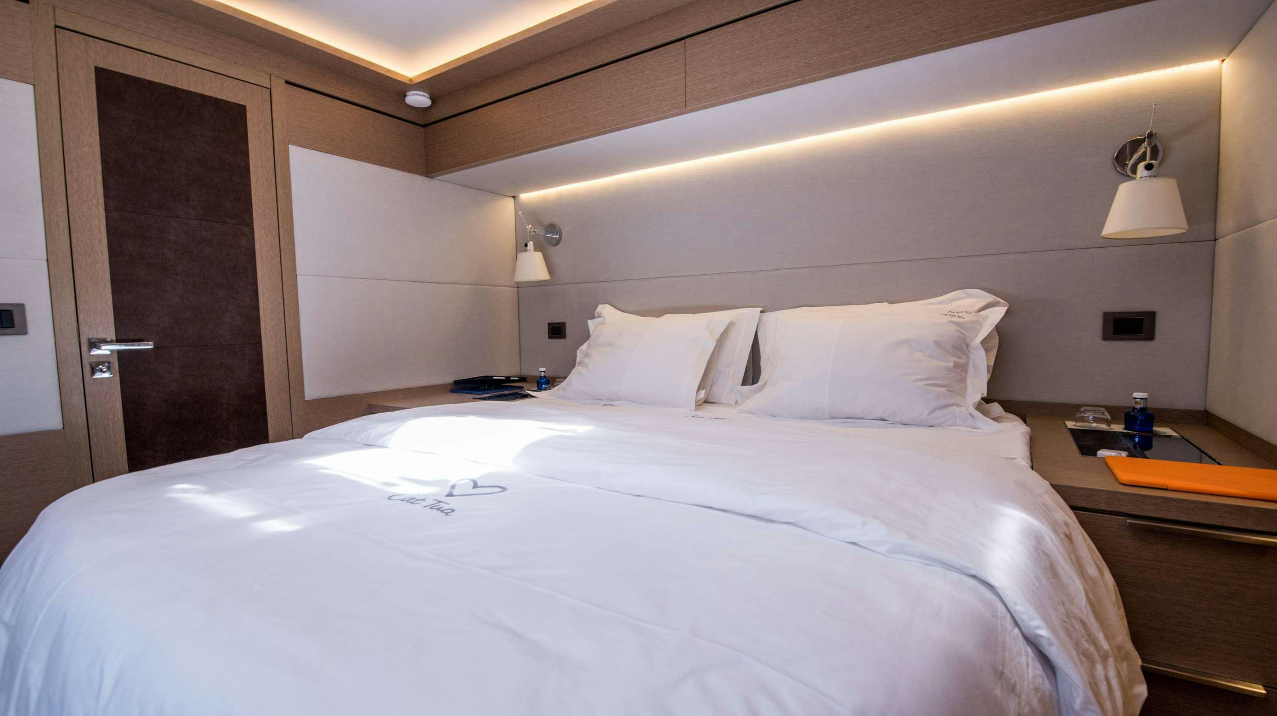 a bed with white sheets aboard CAT TUA Yacht for Charter