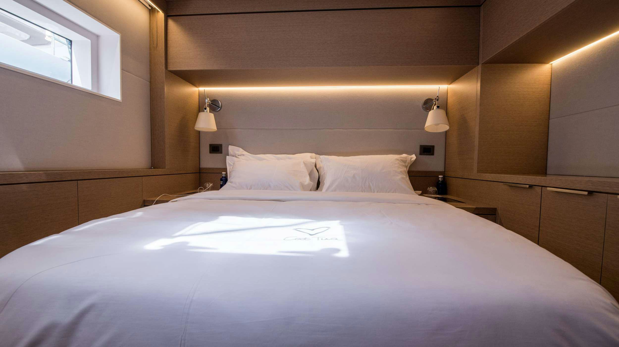 a bed with white sheets aboard CAT TUA Yacht for Charter