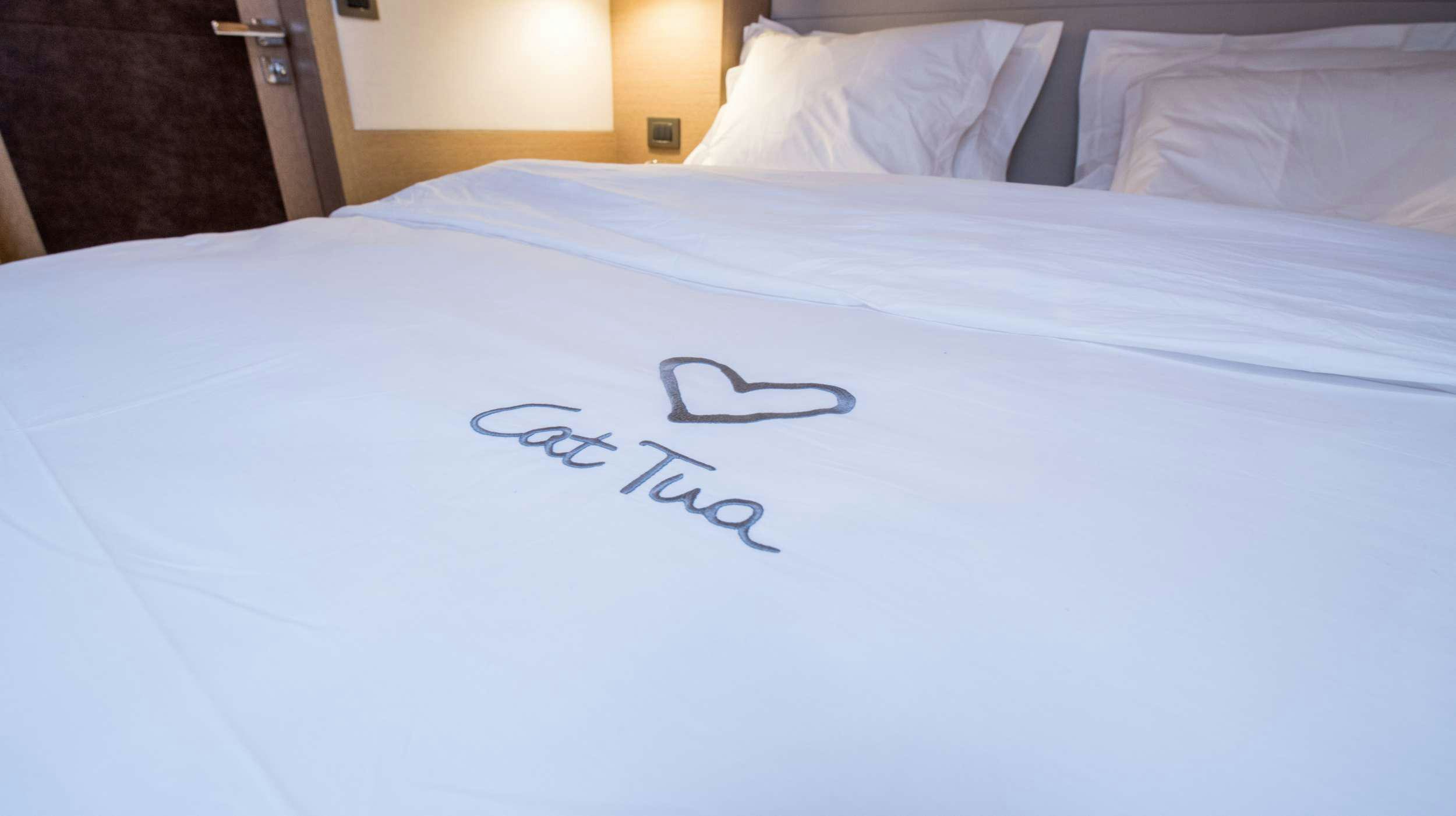 a bed with white sheets aboard CAT TUA Yacht for Charter