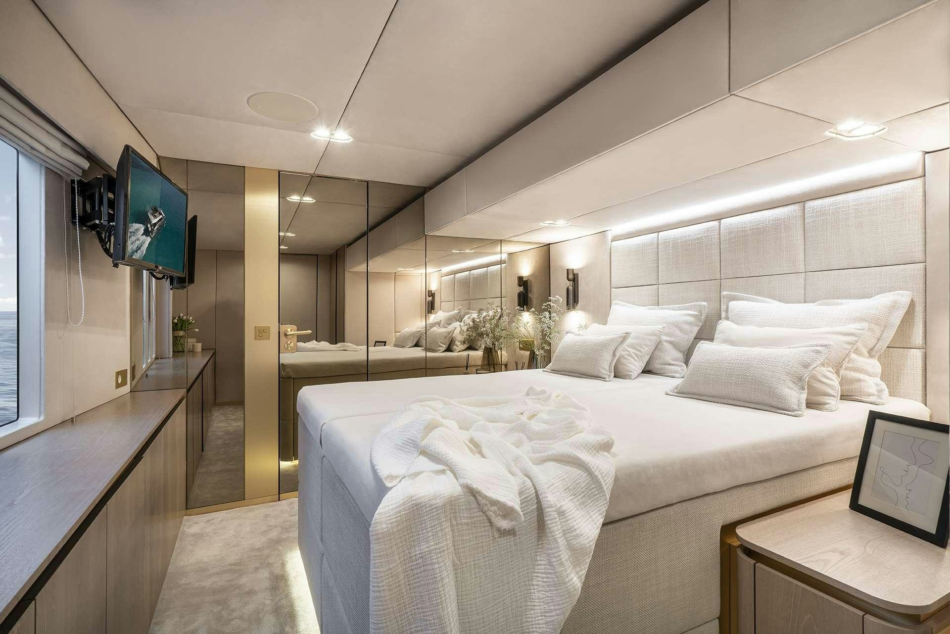 a room with a bed and a tv on the wall aboard MANTA Yacht for Charter
