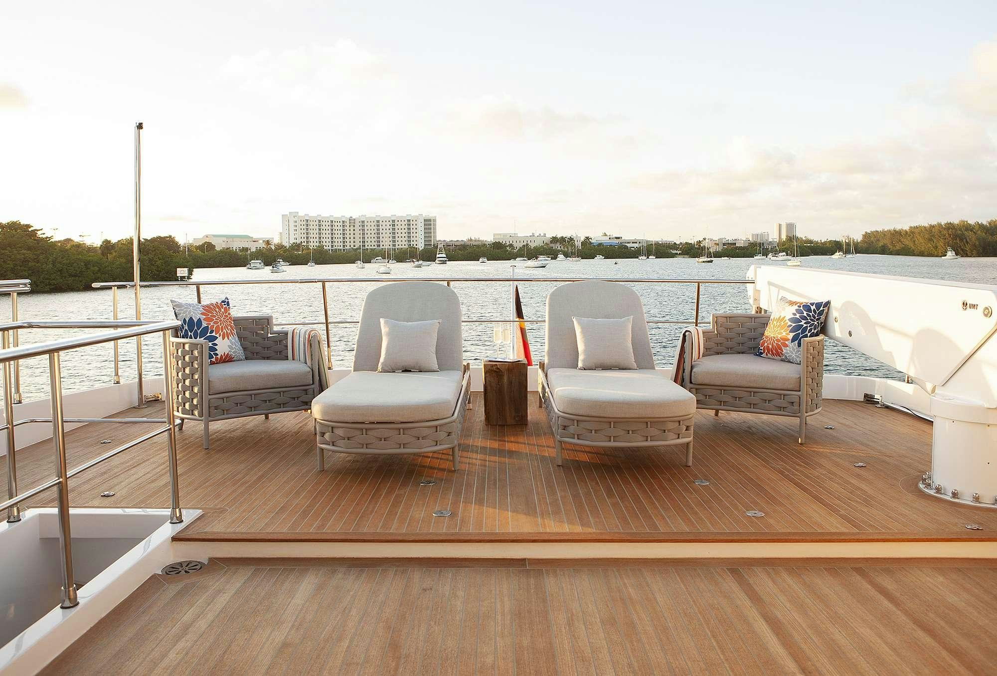 a deck with chairs and a body of water aboard DADDY Yacht for Charter