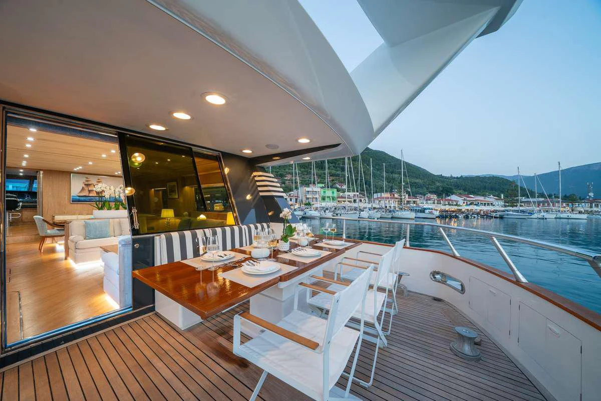 a large room with a table and chairs and a large ship in the water aboard OPERA Yacht for Charter