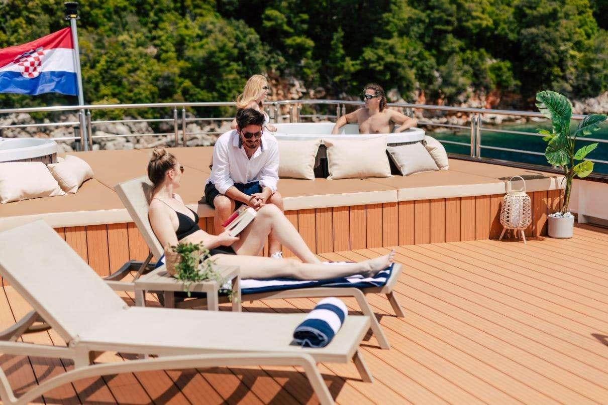 a group of people sitting on lounge chairs on a deck aboard SYMPHONY Yacht for Charter