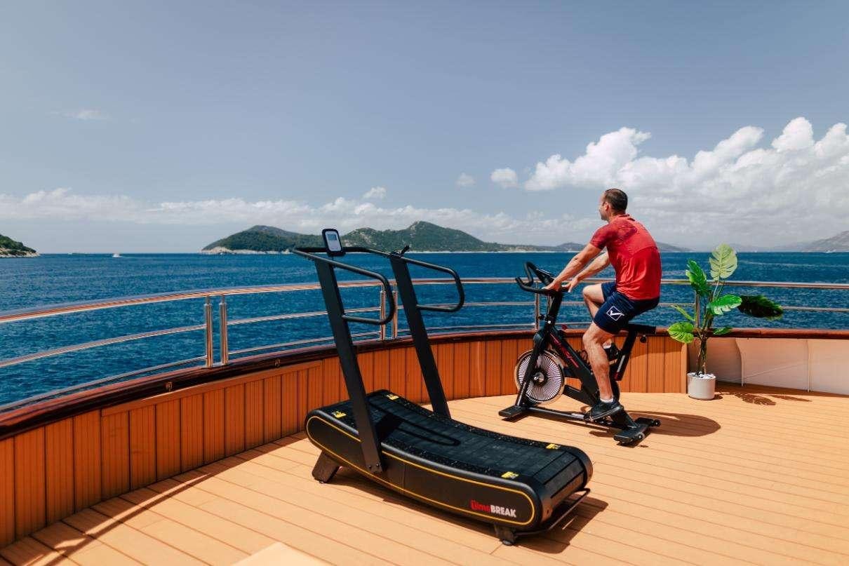 a person riding a bicycle on a boardwalk next to a body of water aboard SYMPHONY Yacht for Charter