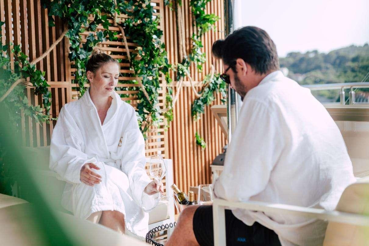 a man and a woman sitting on a balcony aboard SYMPHONY Yacht for Charter