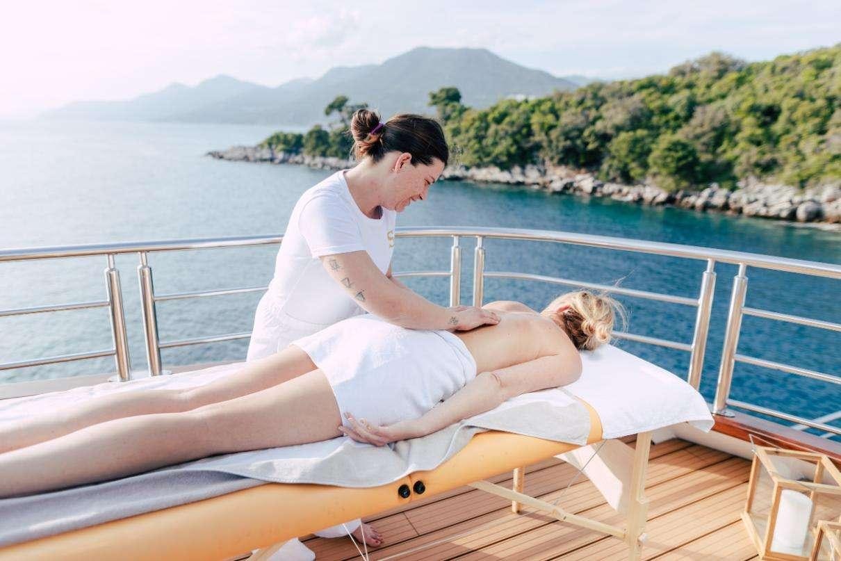 a man and woman sitting on a lounge chair on a dock aboard SYMPHONY Yacht for Charter