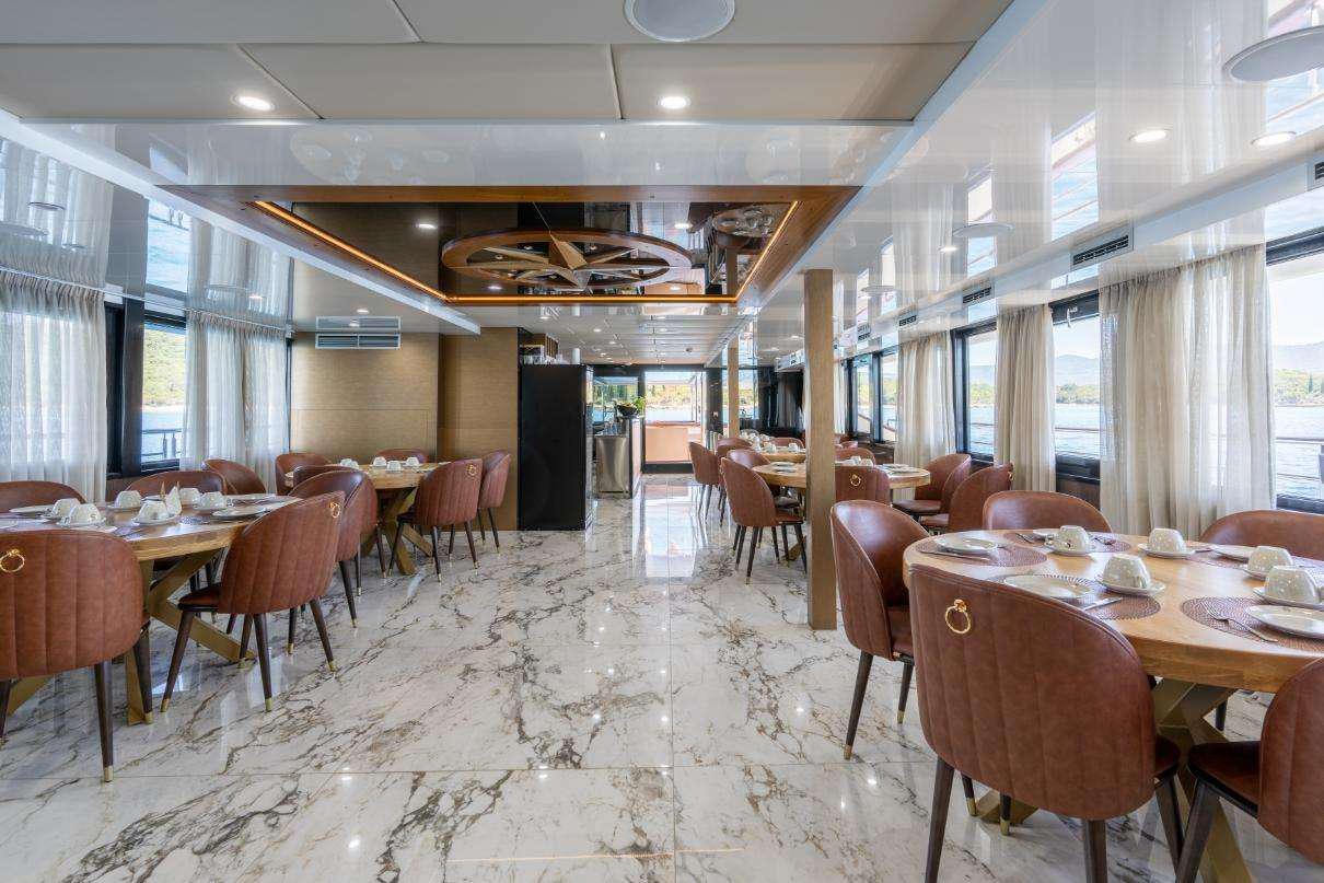 a room with tables and chairs aboard SYMPHONY Yacht for Charter