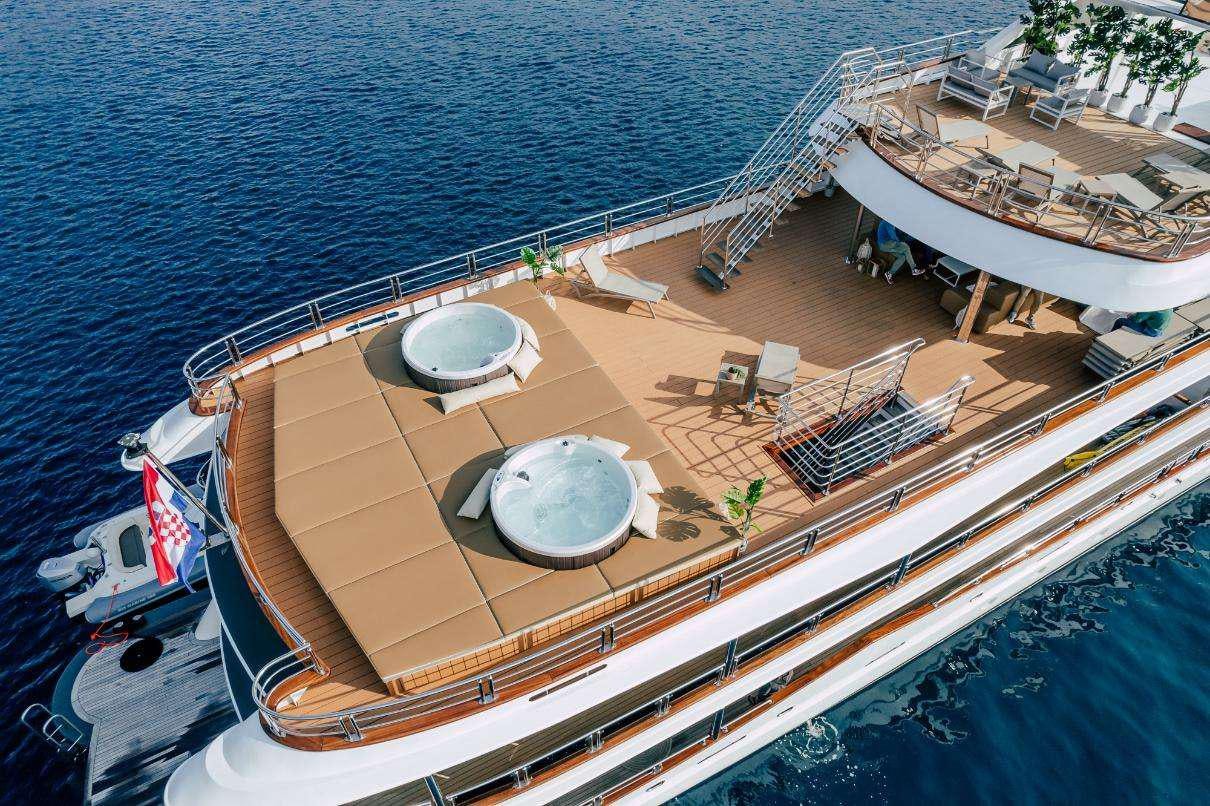a deck with a chair and a table on it by the water aboard SYMPHONY Yacht for Charter