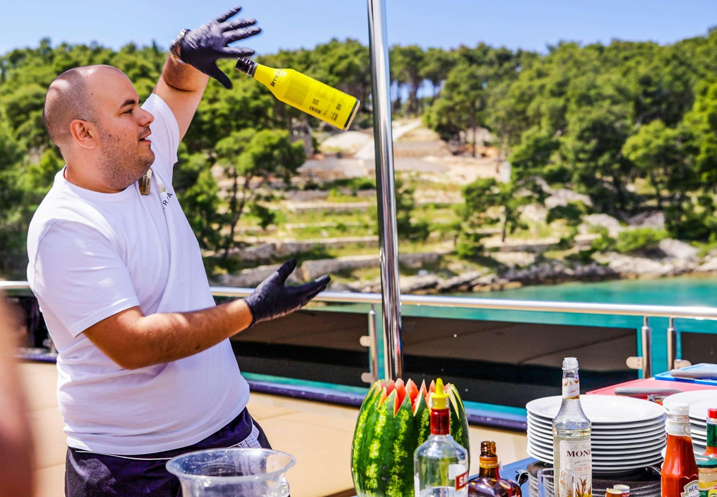 a man pouring a drink into a bottle aboard ARETHA Yacht for Charter