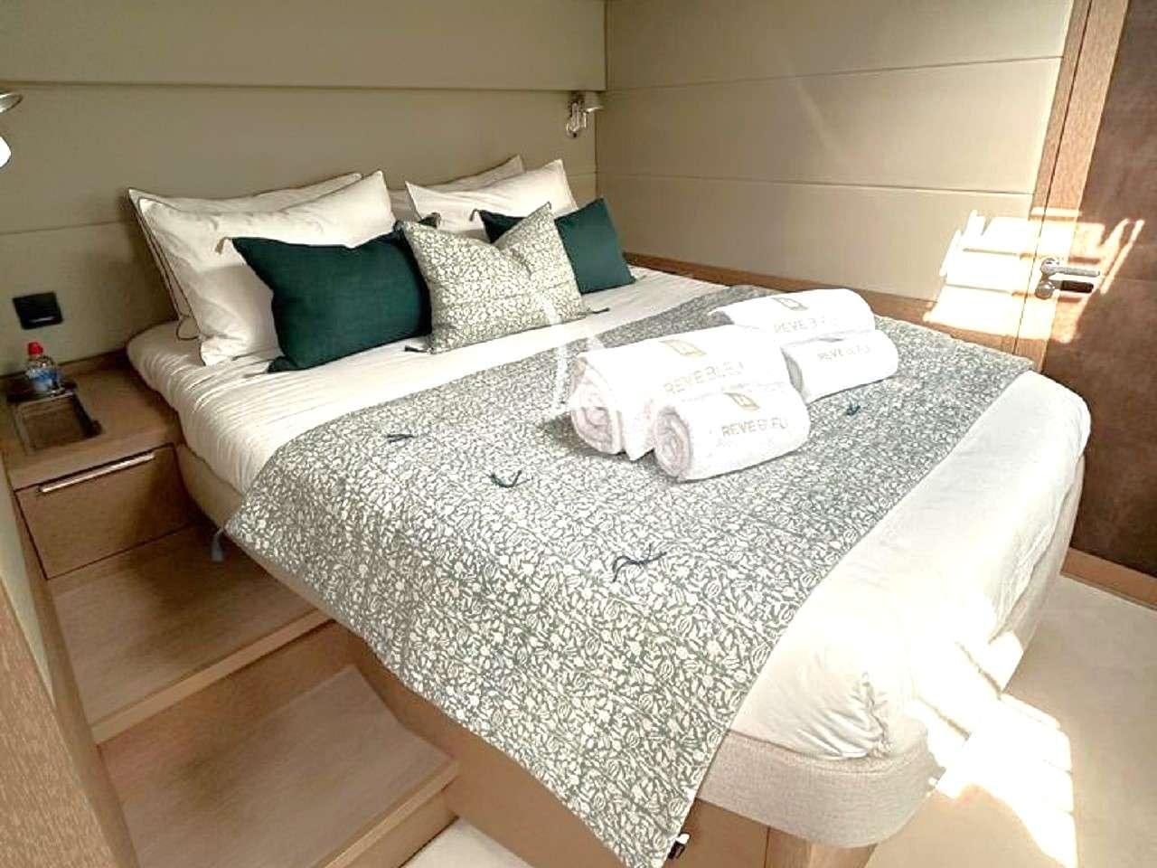 a bed with white sheets and pillows aboard REVE BLEU Yacht for Charter