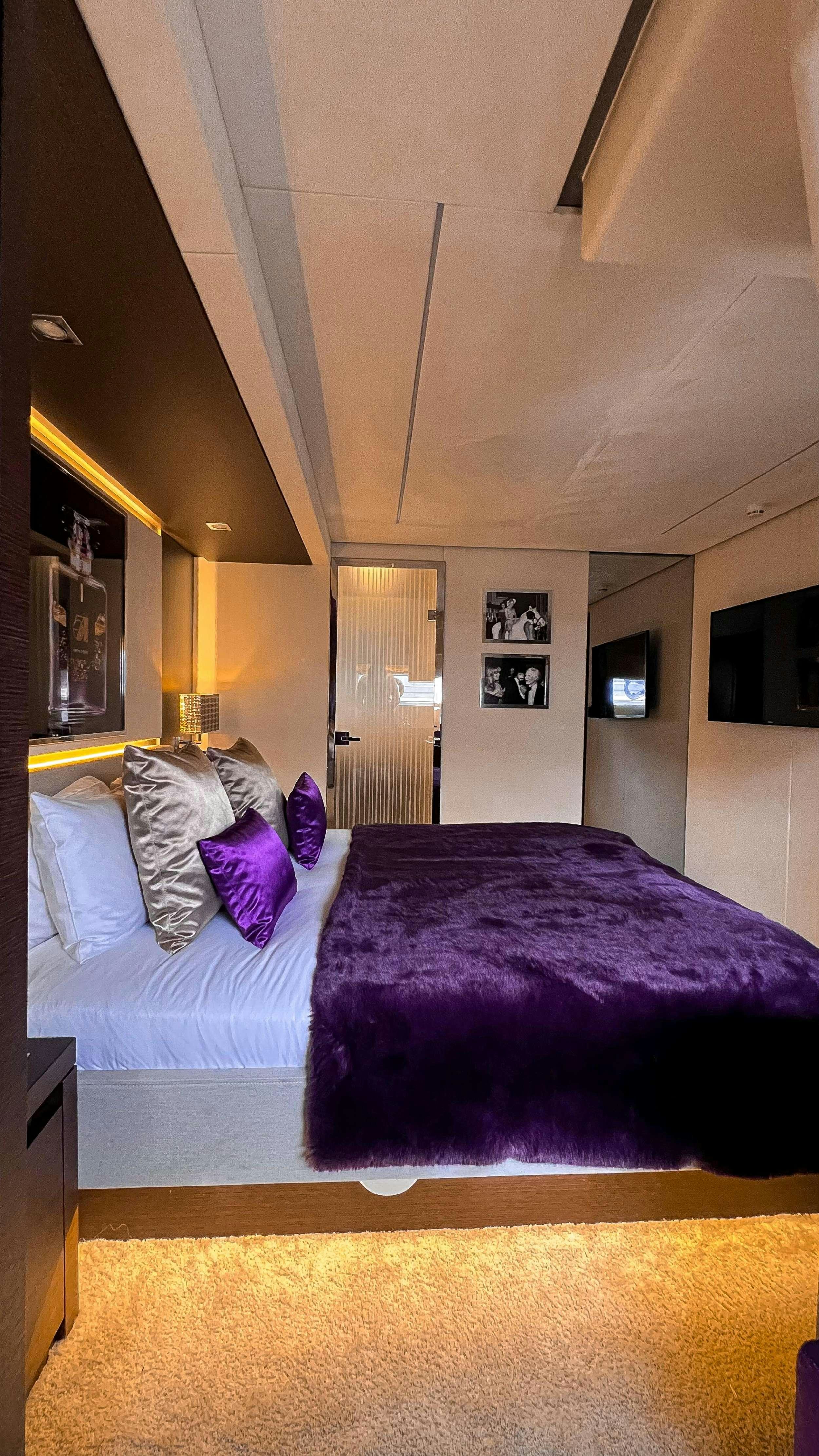 a bed with purple sheets aboard ROMY ONE Yacht for Charter