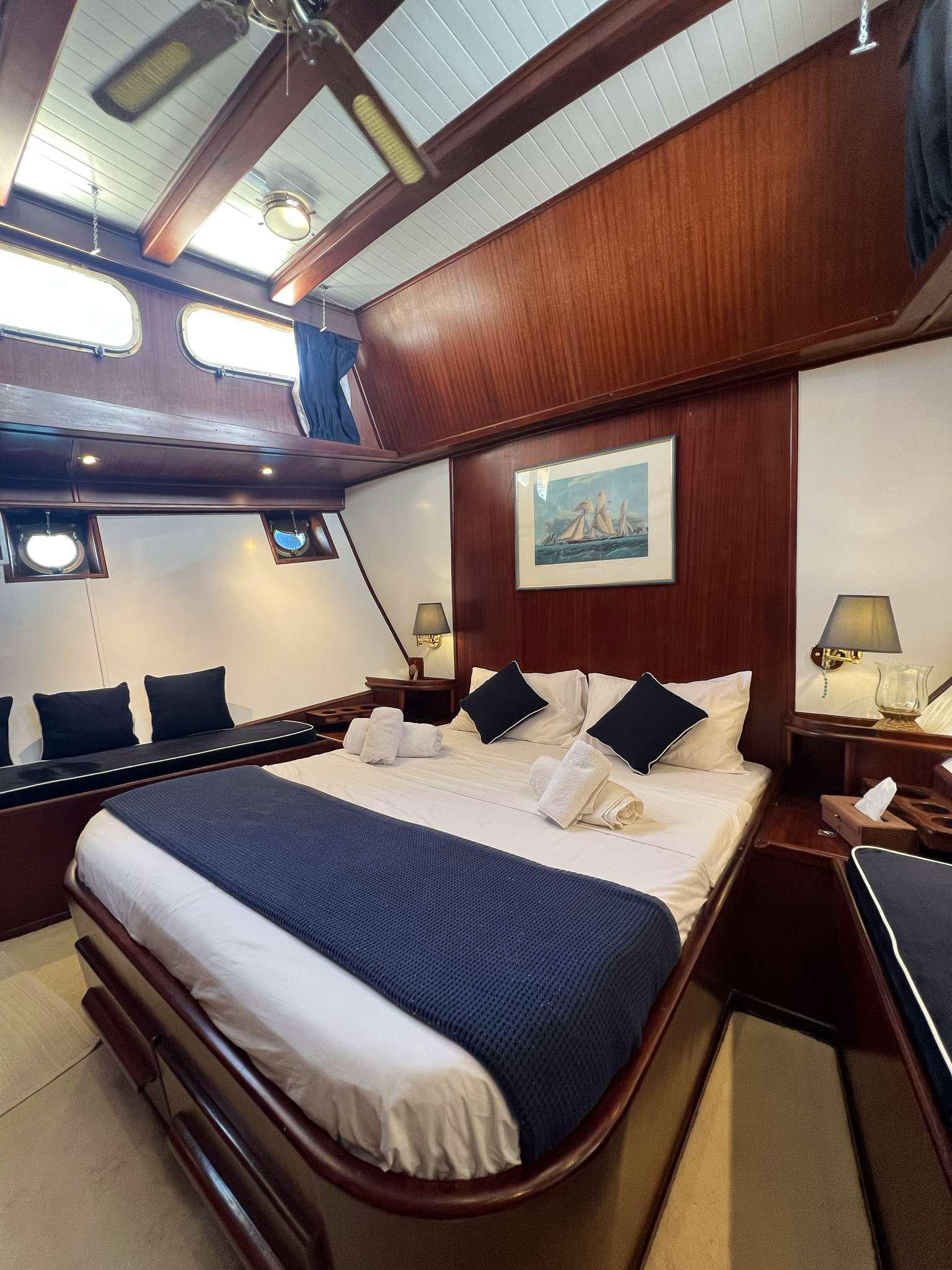 a bed with a blue and white bed spread aboard APHRODITE Yacht for Charter