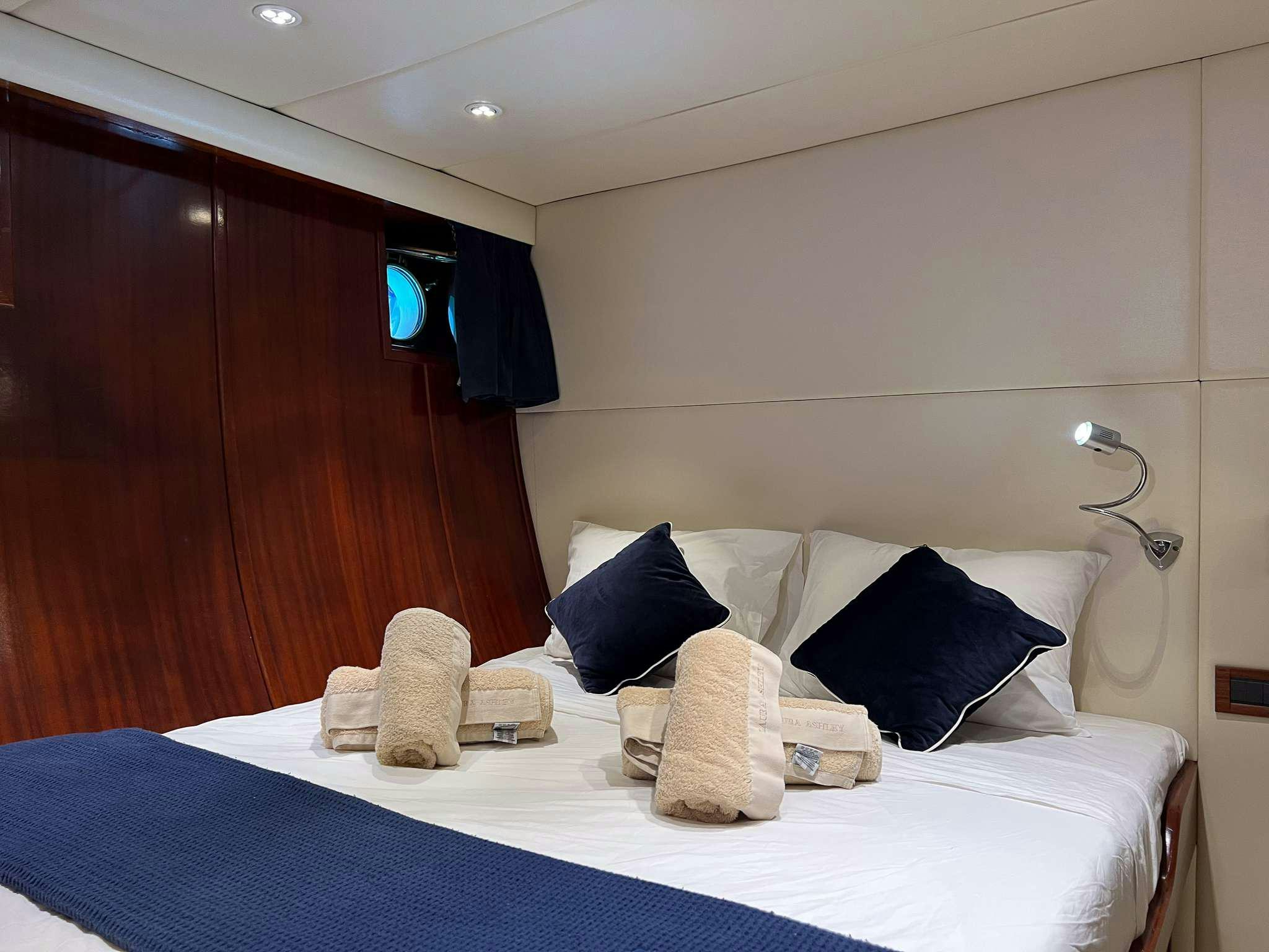 a bed with a blue sheet and pillows aboard APHRODITE Yacht for Charter