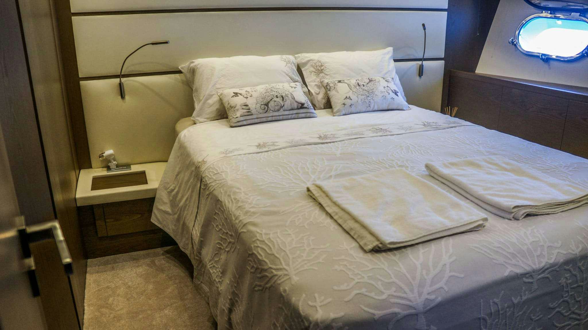 a bed with white sheets aboard KUUM Yacht for Charter