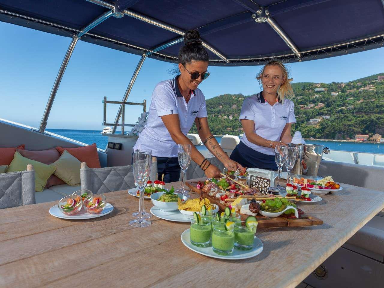 a man and woman sitting at a table with food and drinks on it aboard MR SEA Yacht for Charter