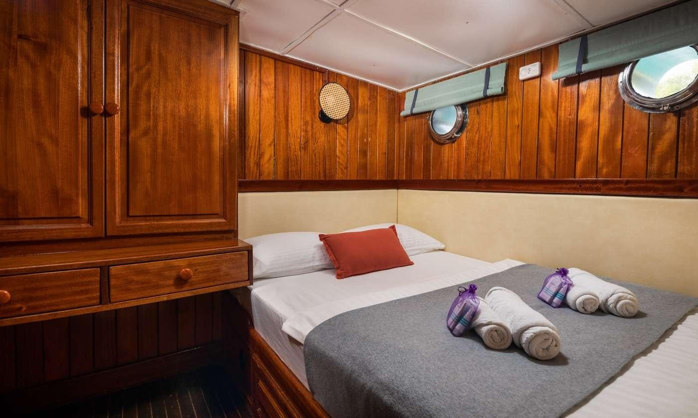 a bed with red pillows aboard GIDEON Yacht for Charter