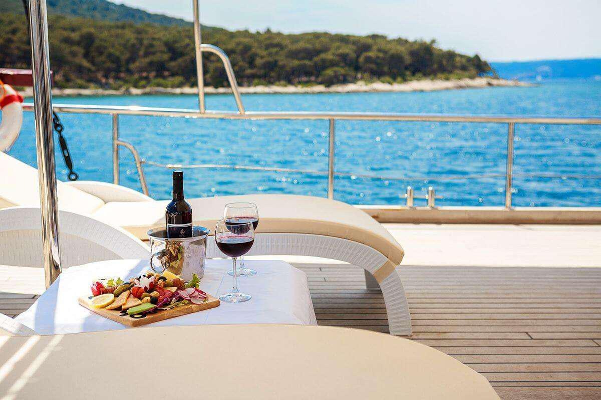 a table with a plate of food and a glass of wine on a boat aboard GIDEON Yacht for Charter
