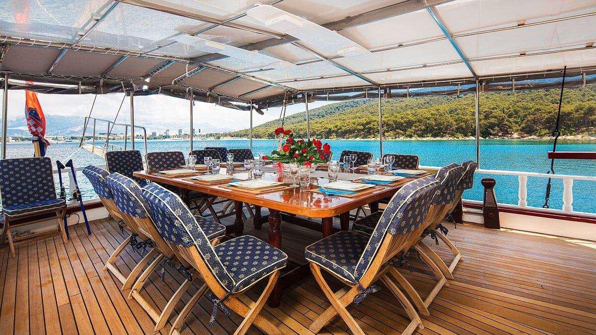 a table set for a meal on a deck overlooking a pool aboard GIDEON Yacht for Charter