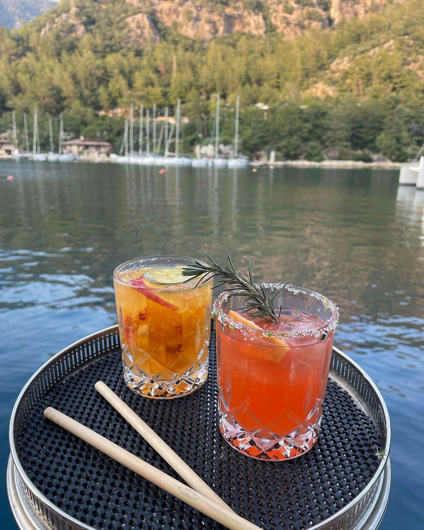 a couple of glasses of beer on a table by a lake aboard JURA II Yacht for Charter