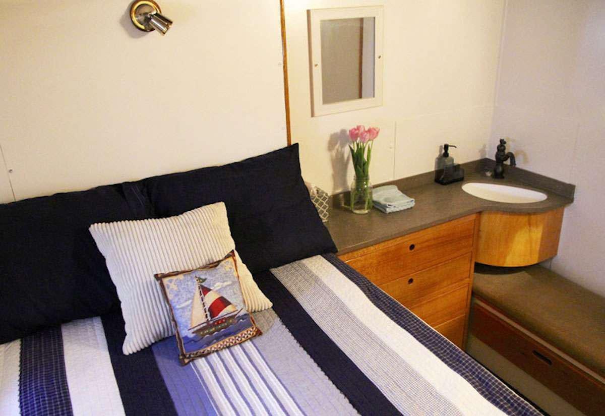 a bed with a black and white striped blanket and a black and white striped pillow on a wooden aboard DISCOVERY Yacht for Charter