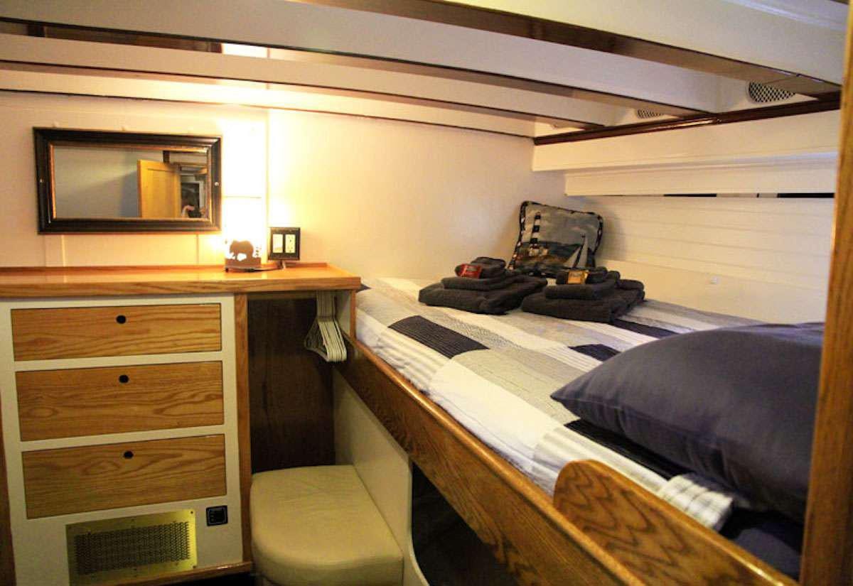 a bedroom with a bed and a dresser aboard DISCOVERY Yacht for Charter