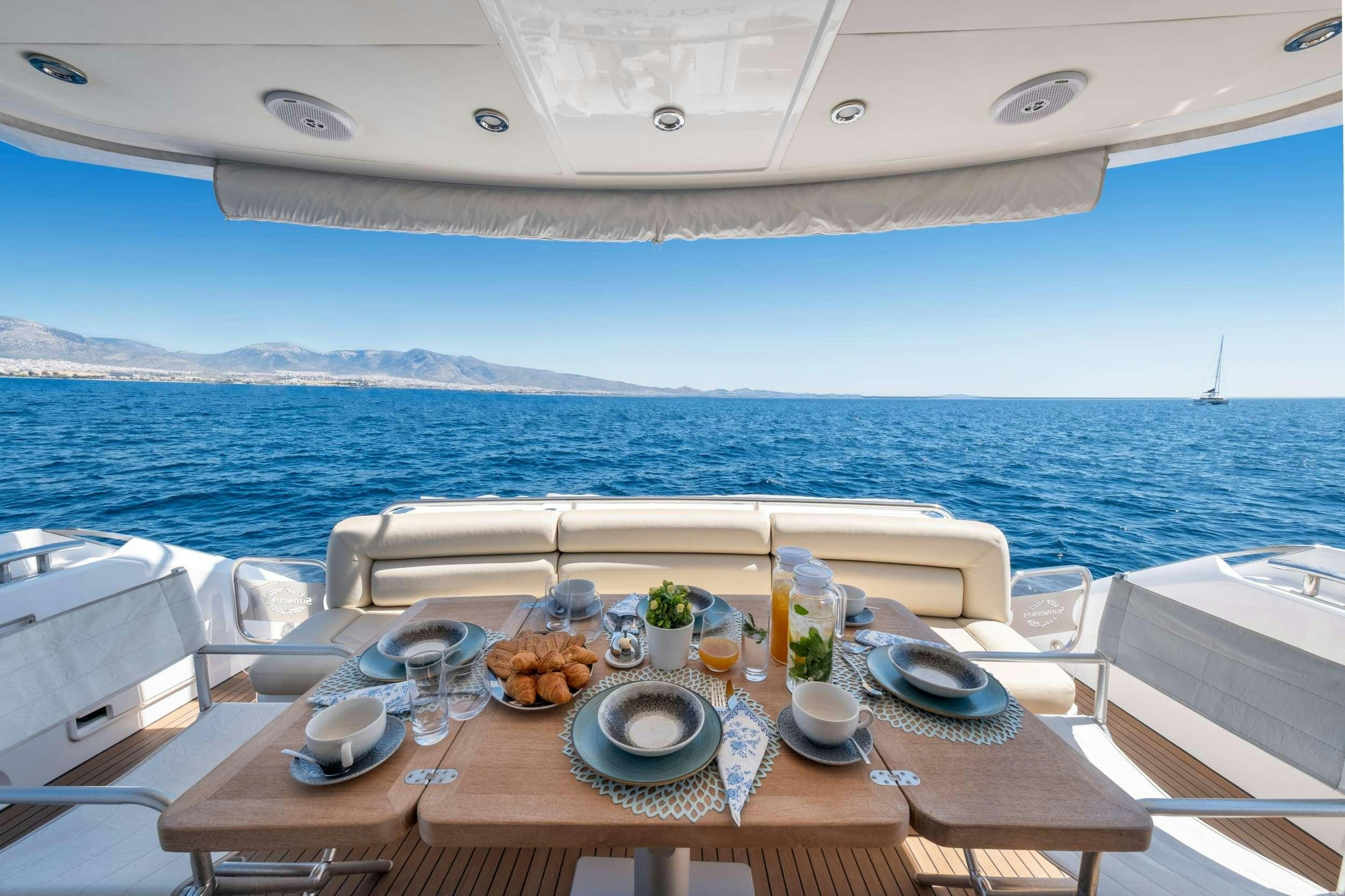 a table with plates and food on it by the ocean aboard POLPO Yacht for Charter