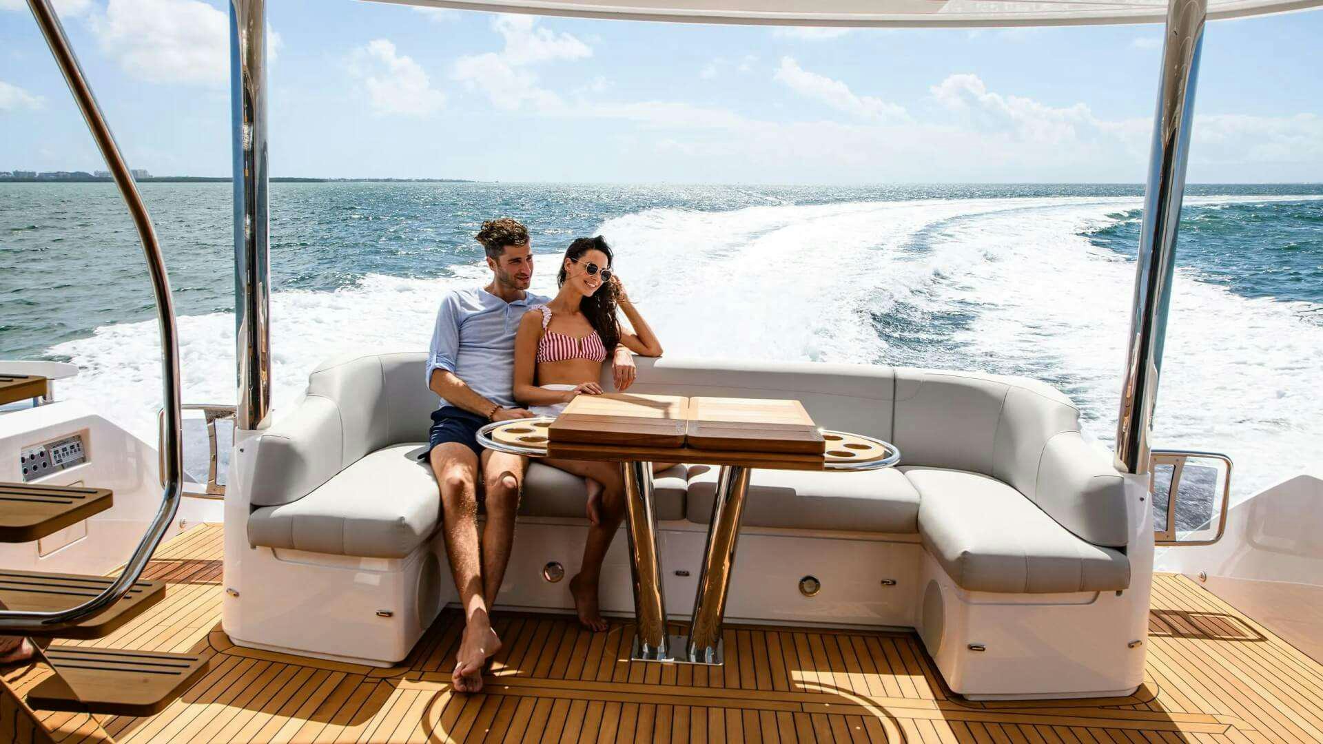 a man and woman sitting on a couch on a boat aboard APOLLO Yacht for Charter