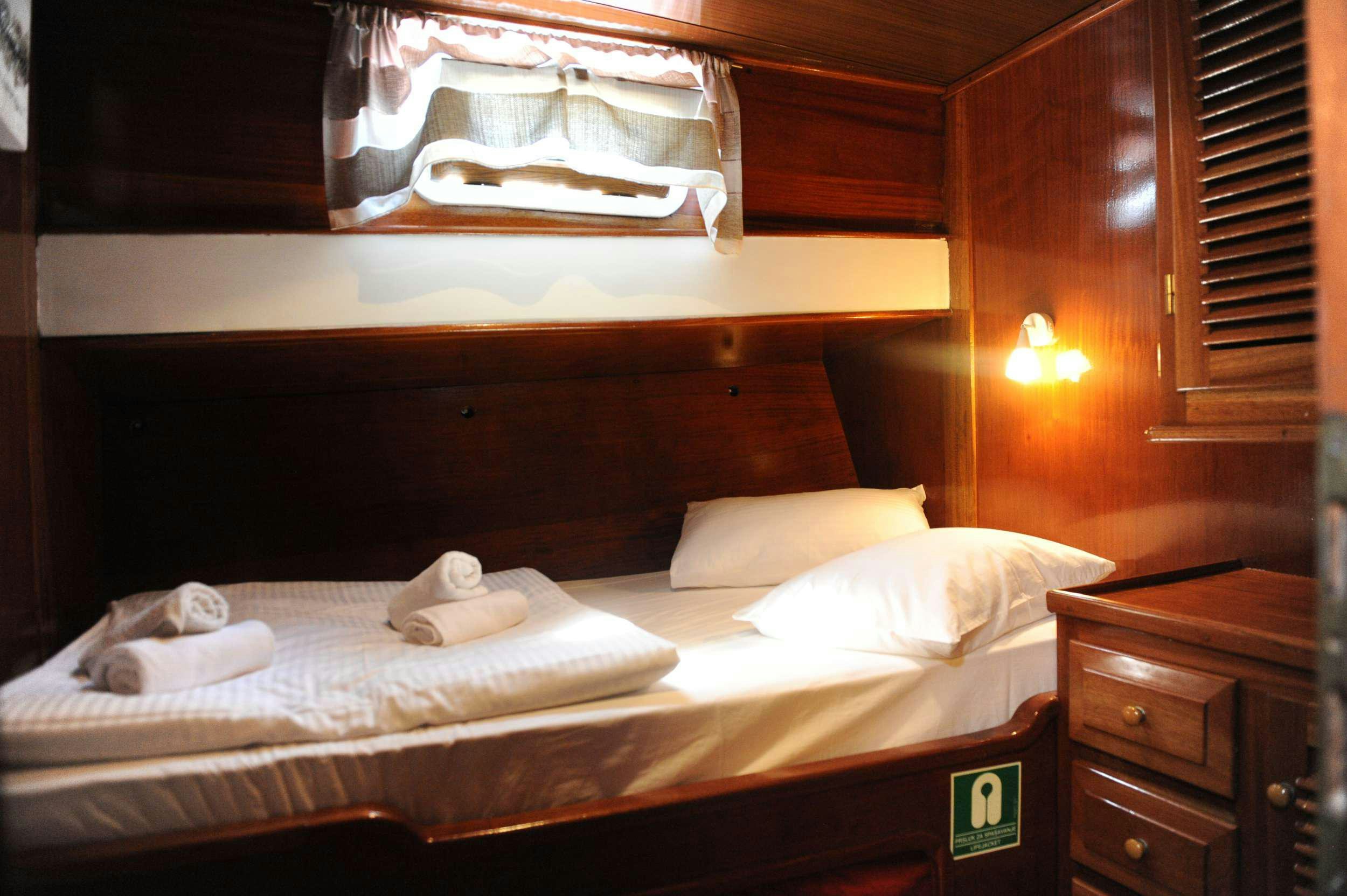 a bed with white sheets aboard AGORA Yacht for Charter