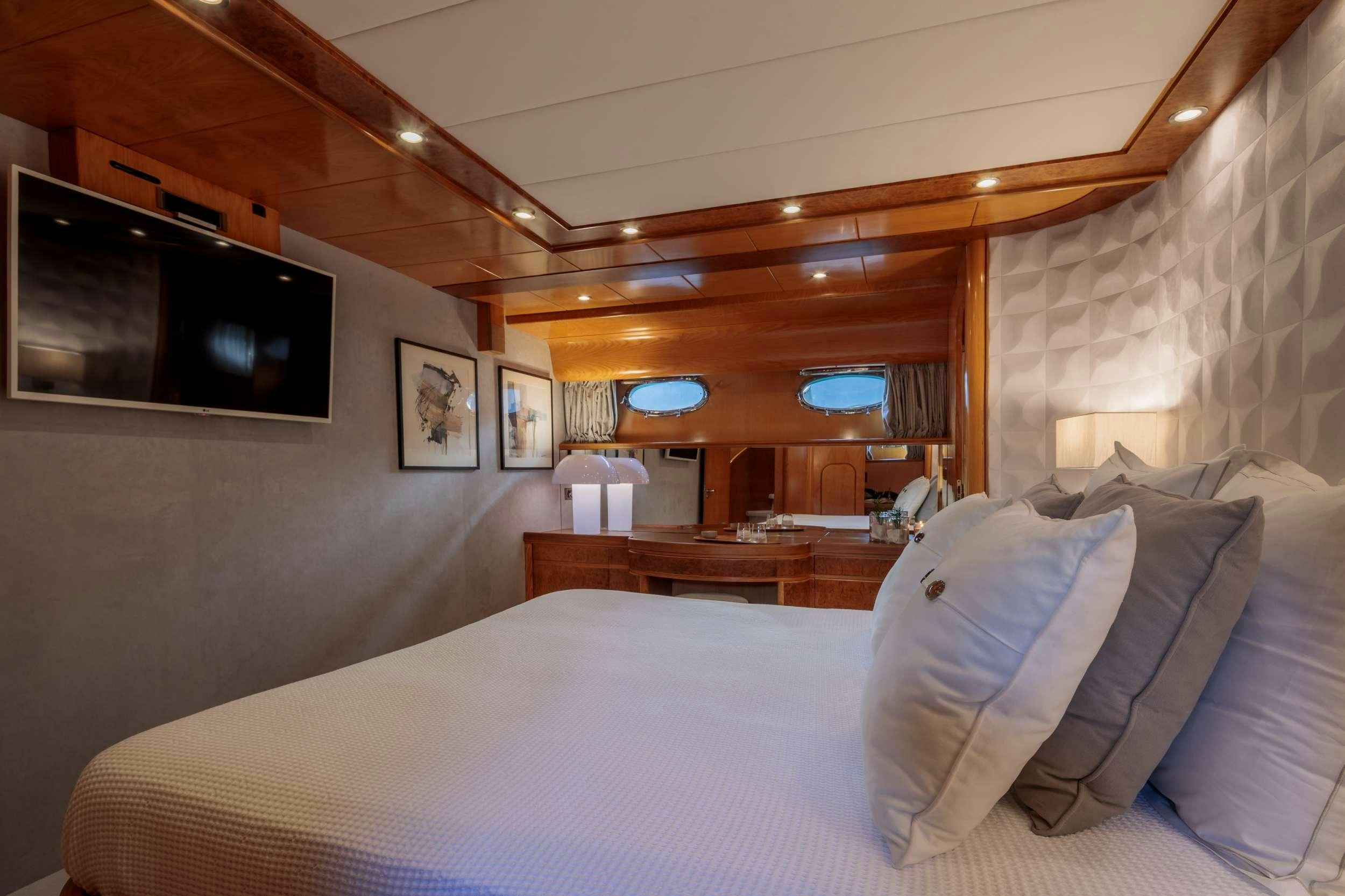 a room with a bed and a television aboard VA BENE Yacht for Charter