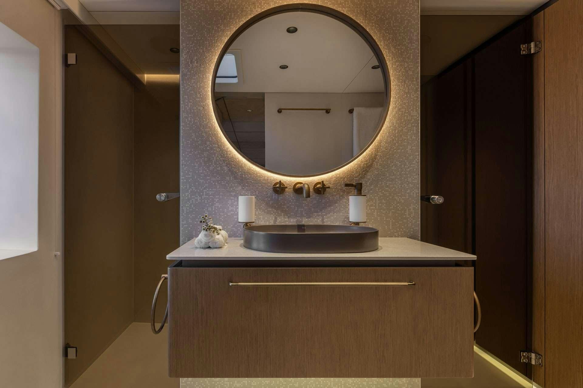 a bathroom with a round mirror aboard OTOCTONE Yacht for Charter
