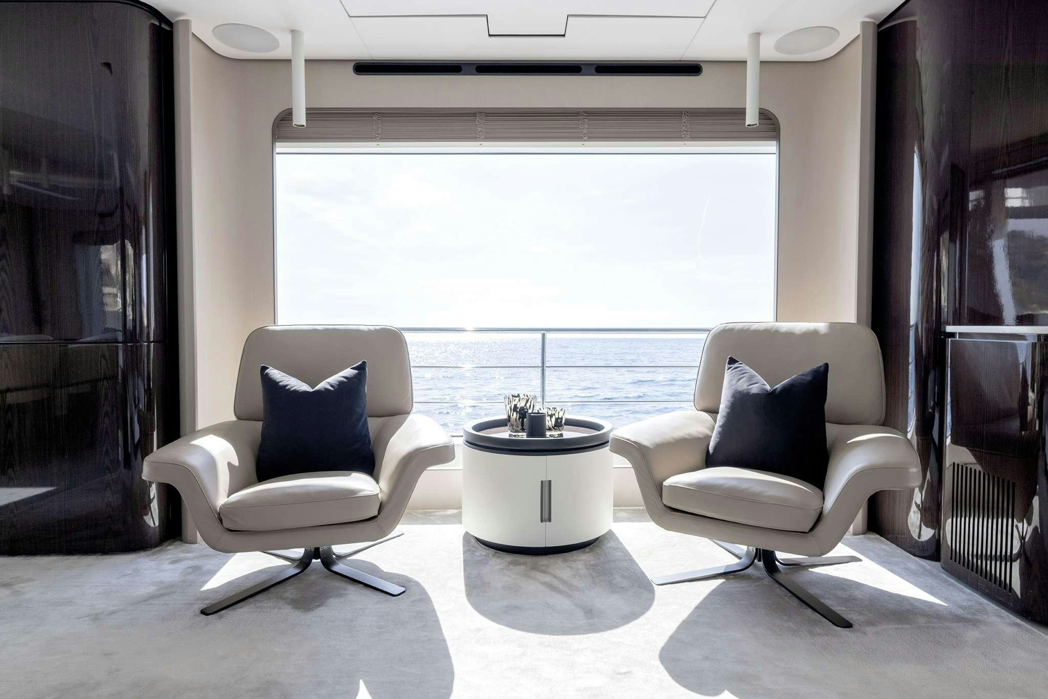 a couple of white chairs in a room with a large window aboard NEMESIS Yacht for Charter