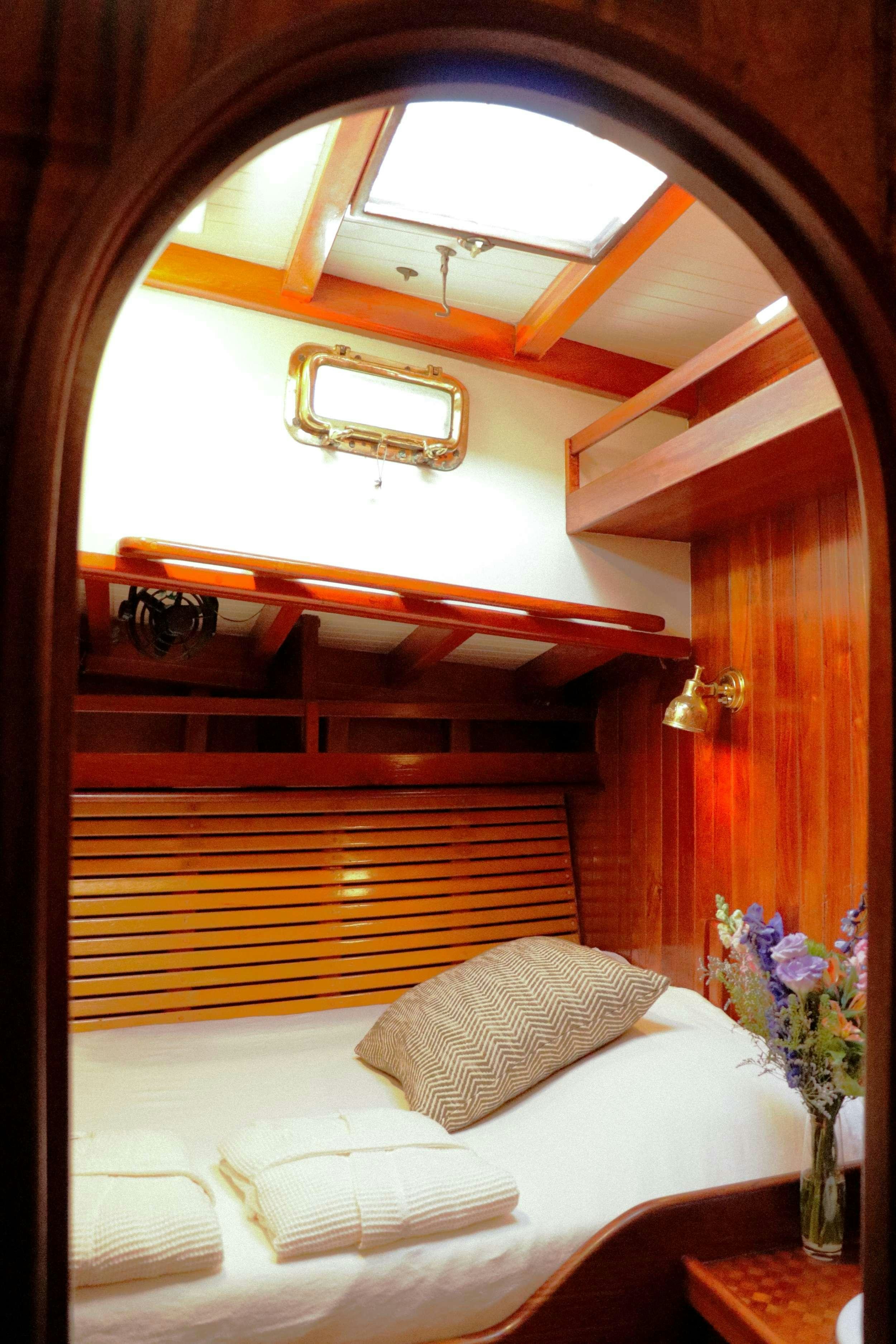 a bed with a white bed and a wooden headboard aboard TREE OF LIFE Yacht for Charter