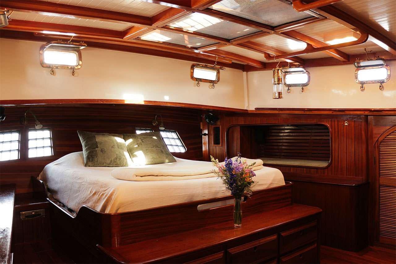 a bed with a table and a vase of flowers on it aboard TREE OF LIFE Yacht for Charter