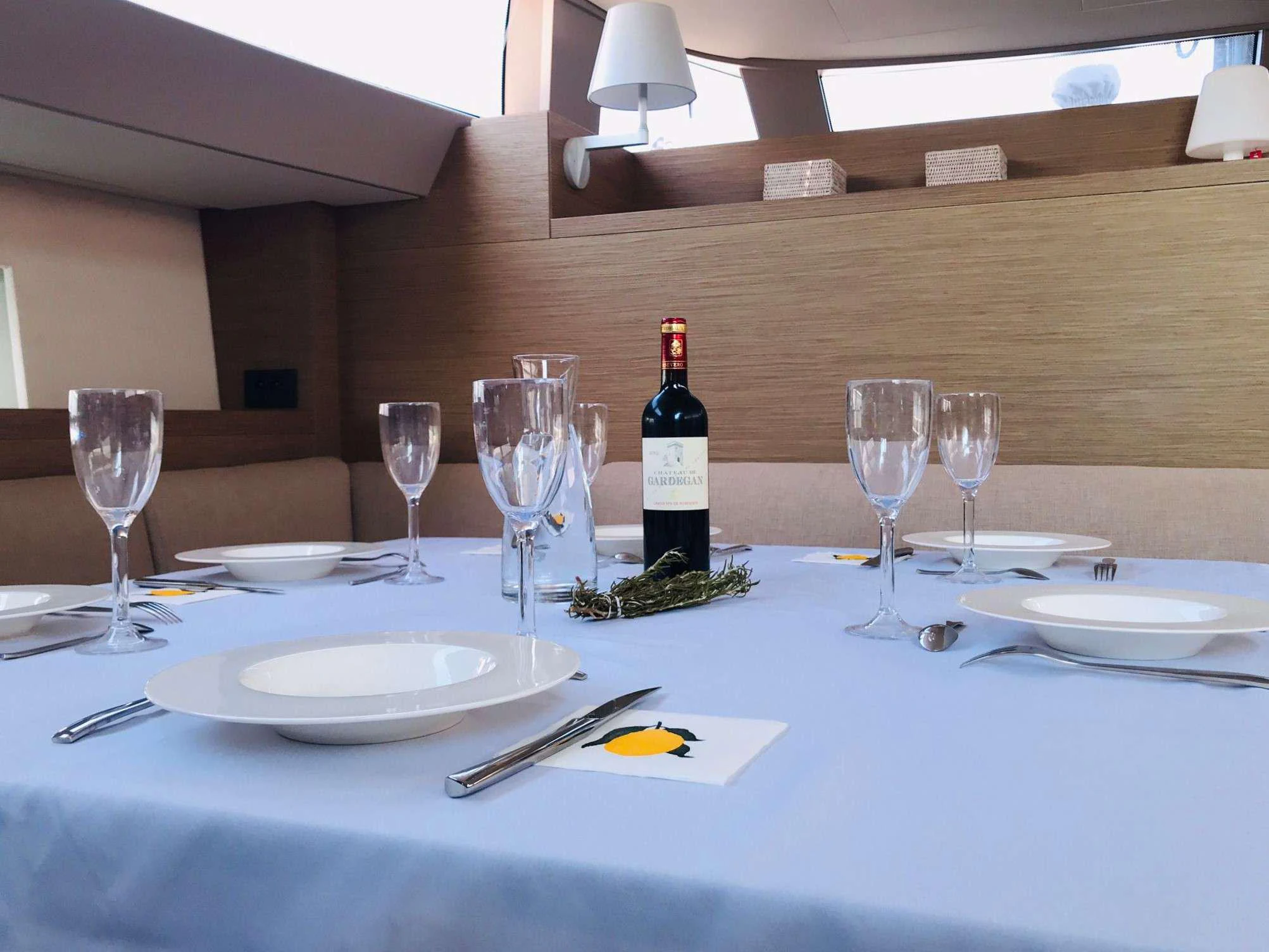 a table with wine glasses and plates aboard MAHINA 3 Yacht for Charter