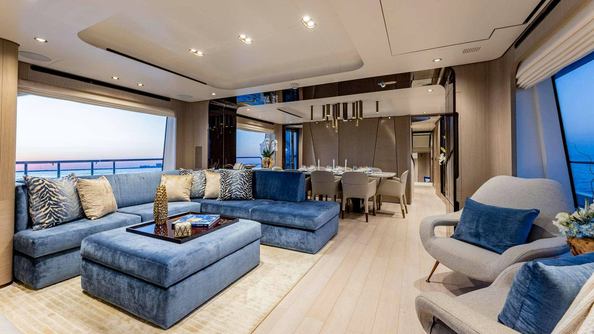 a living room with a blue couch and a large window aboard 4 PLAY Yacht for Charter