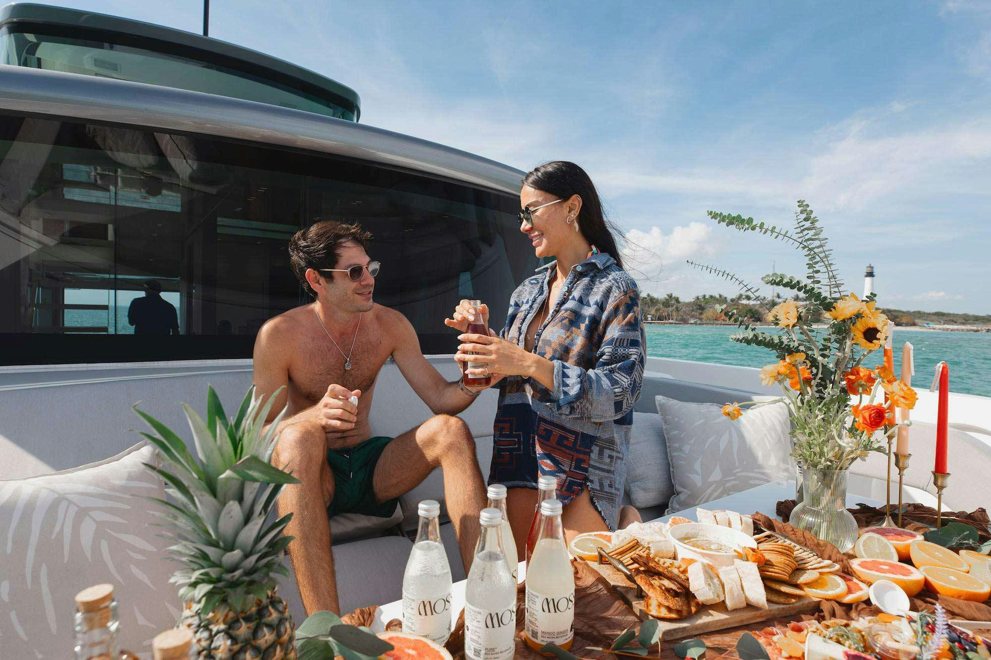 a man and woman sitting at a table with food and drinks on it aboard QUARANTENA Yacht for Charter