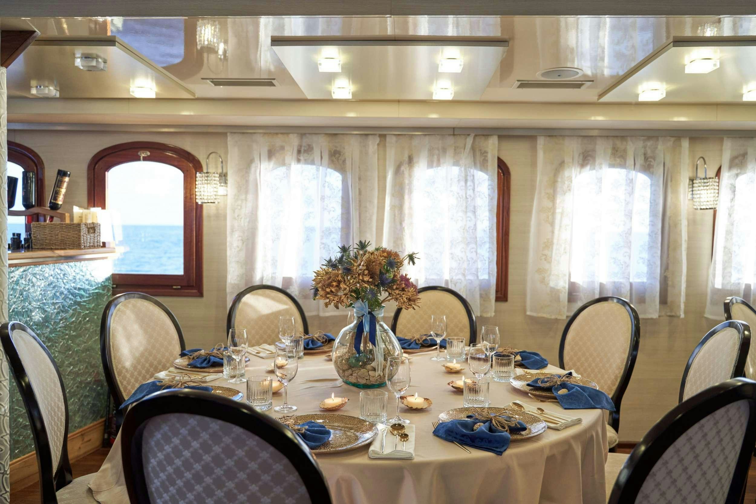a dining room table with a vase of flowers and glasses aboard CASABLANCA Yacht for Charter