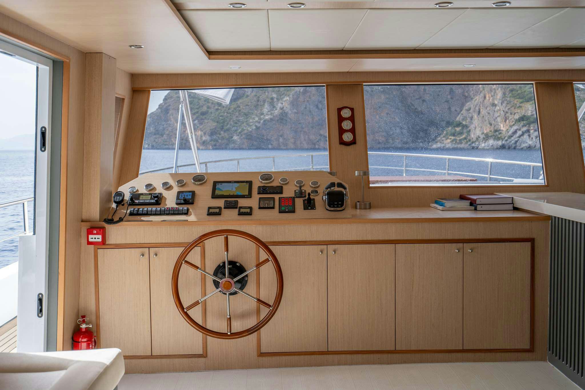 a wooden room with a large wooden wheel and a large window aboard LAVIN Yacht for Charter