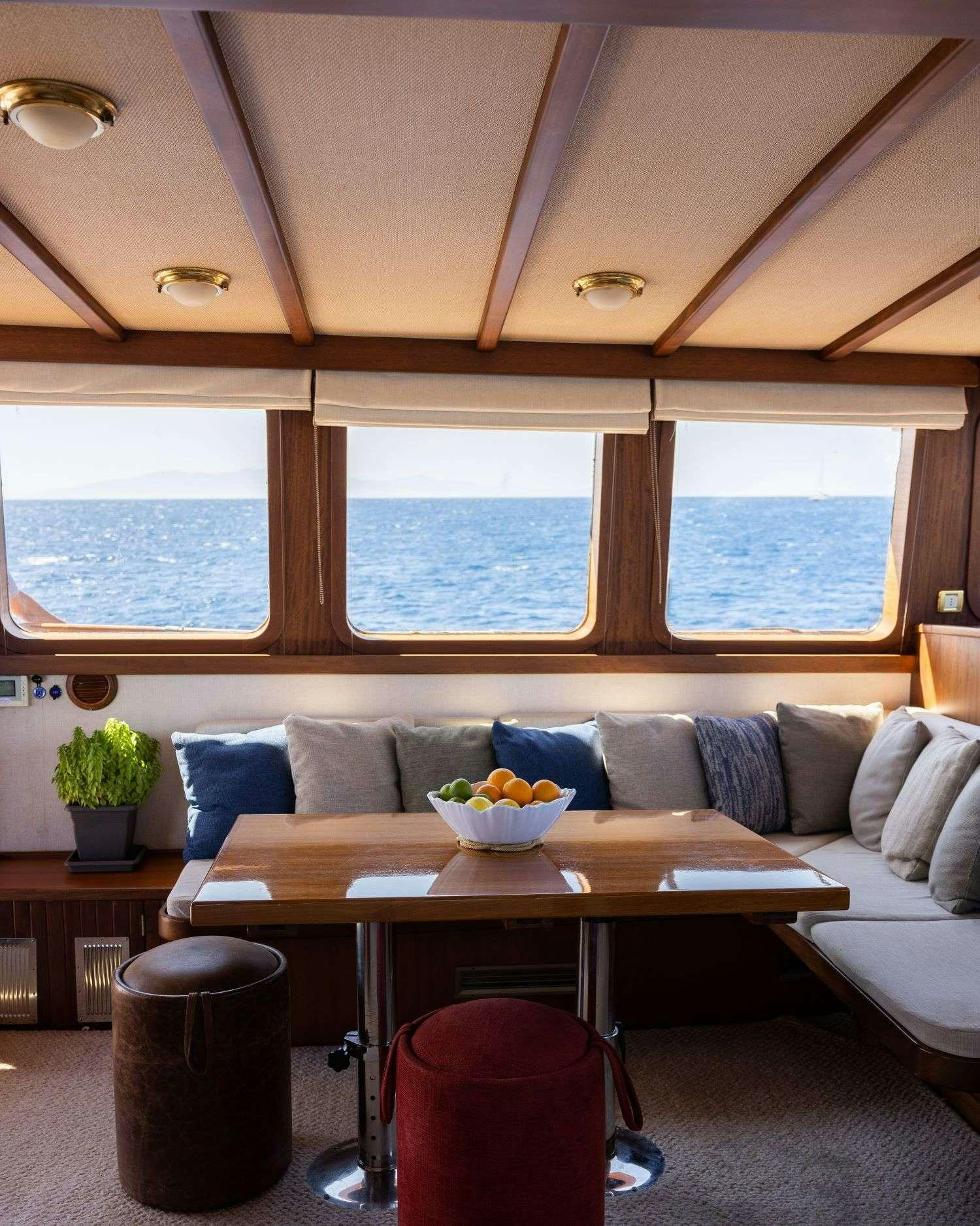 a room with a couch and a table with a bowl of fruit aboard SEATZEN Yacht for Charter