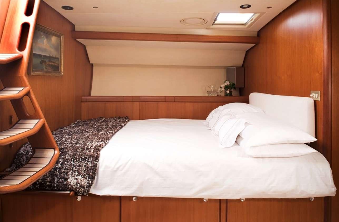 a room with a bed and a chair aboard ABEON Yacht for Charter