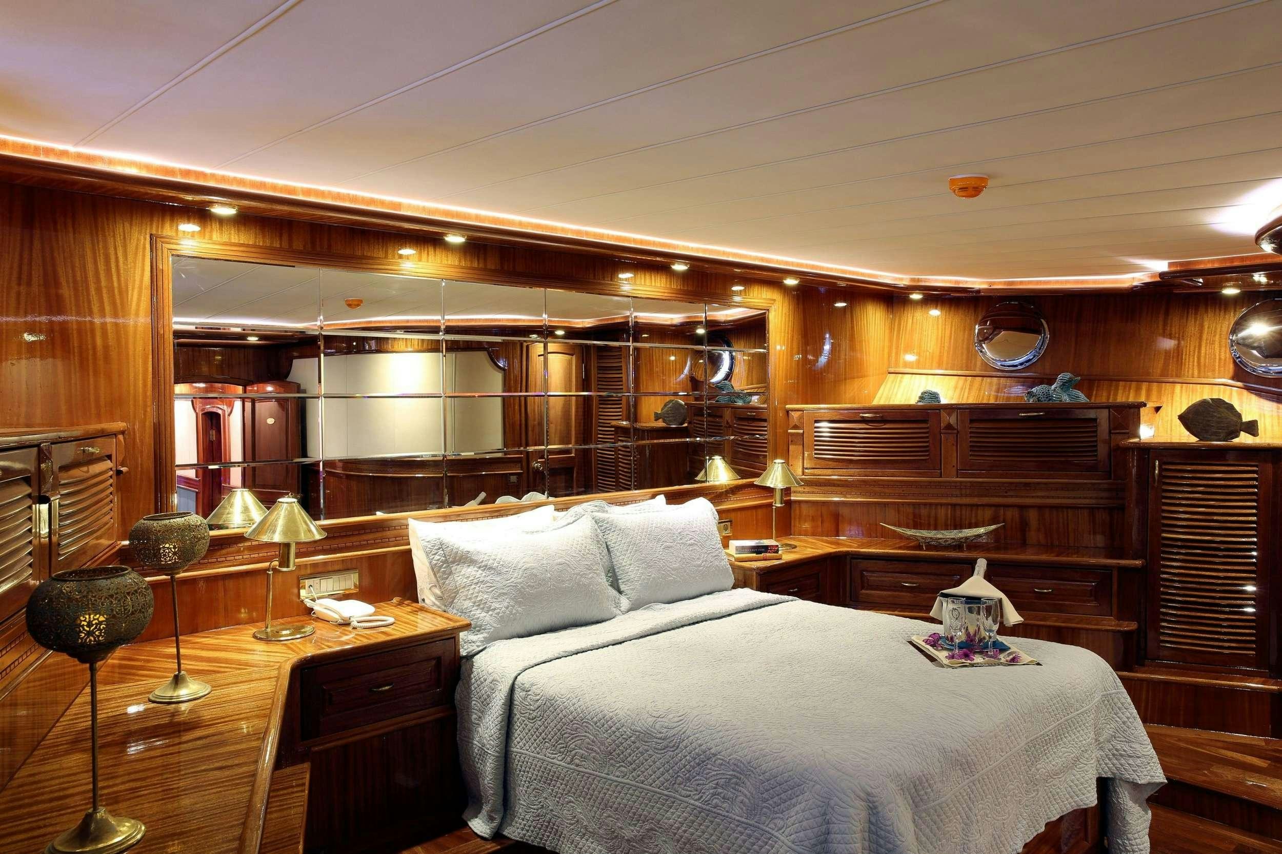 a bed with a white sheet and pillows in a cabin aboard QUEEN ATLANTIS Yacht for Charter