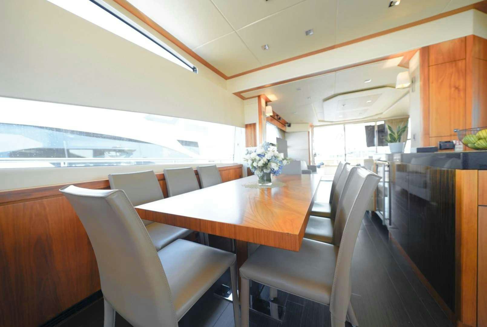 a dining table and chairs in a room with a large window aboard CATCH THE WAVE Yacht for Charter