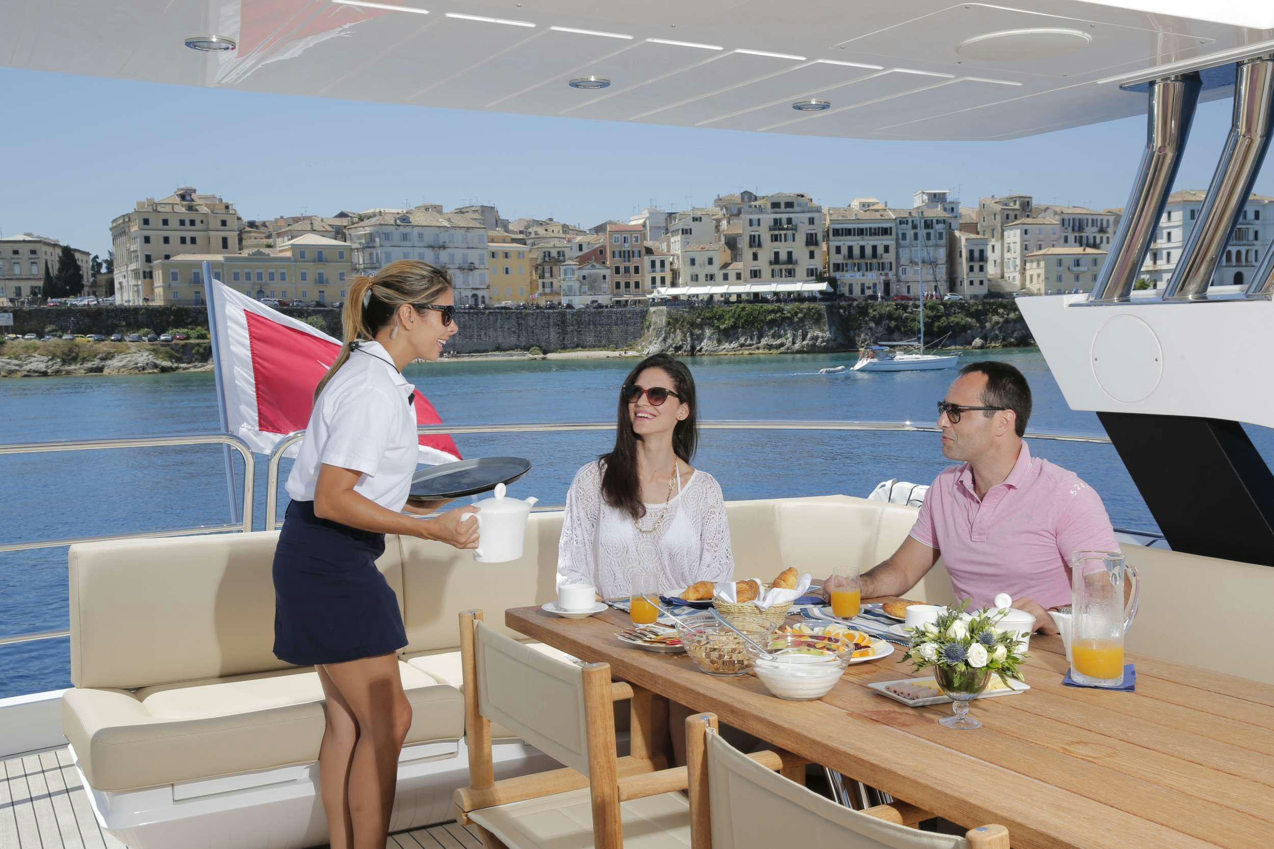 a group of people sitting at a table with drinks and a city in the background aboard FINEZZA Yacht for Charter