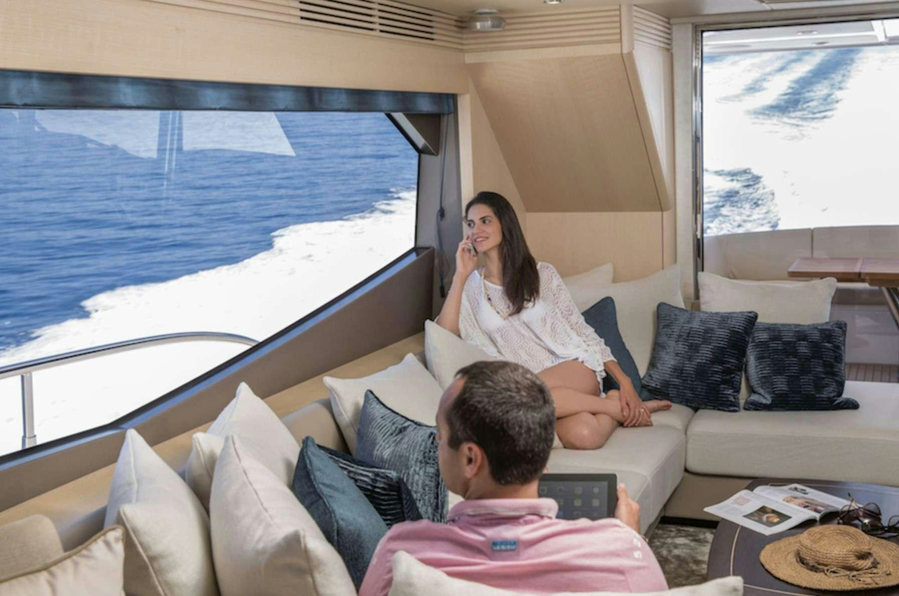 a man and woman sitting on a couch looking at a laptop aboard FINEZZA Yacht for Charter