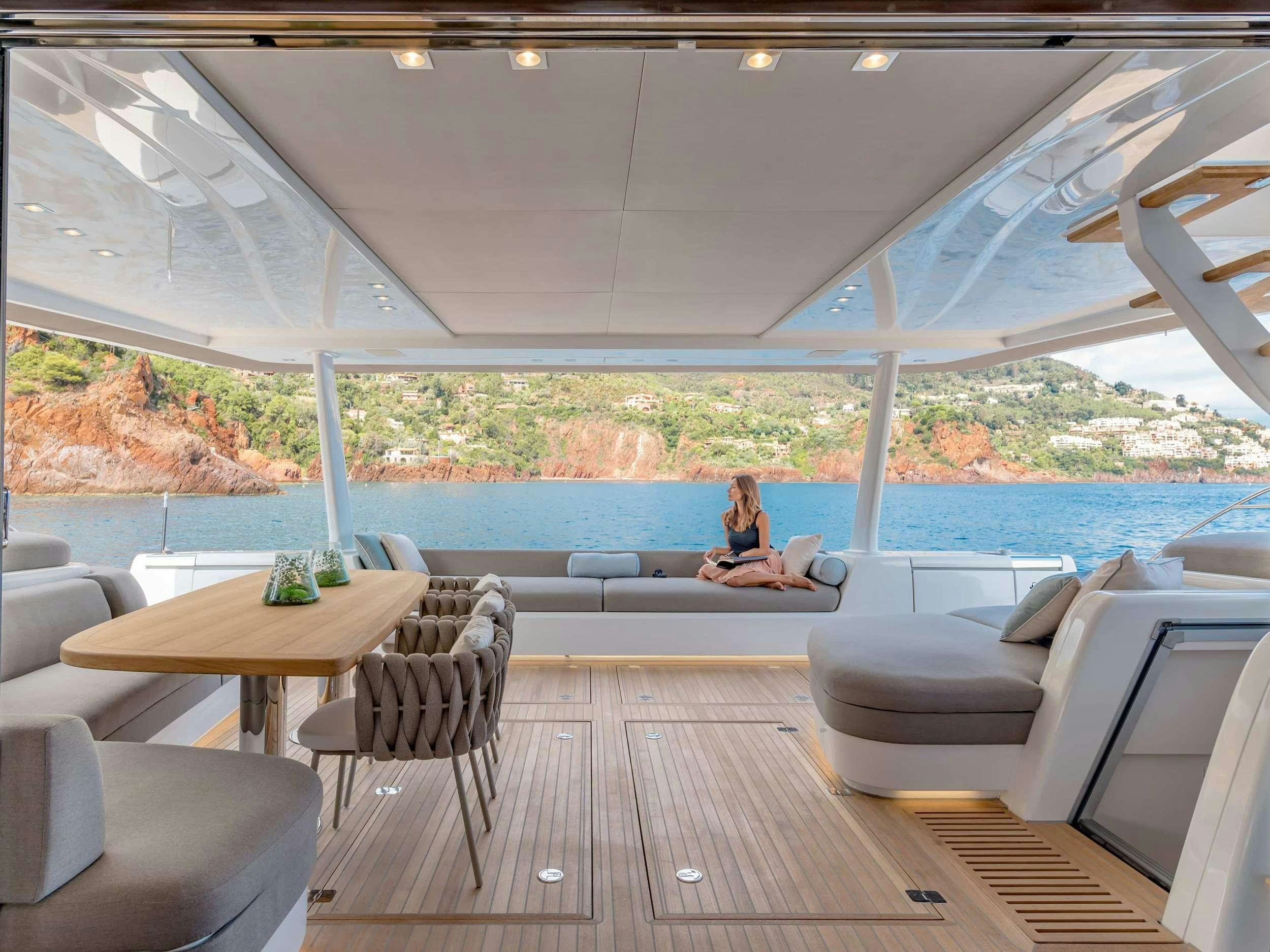 a person sitting on a couch on a deck overlooking a large pool aboard SIETE MARES Yacht for Charter