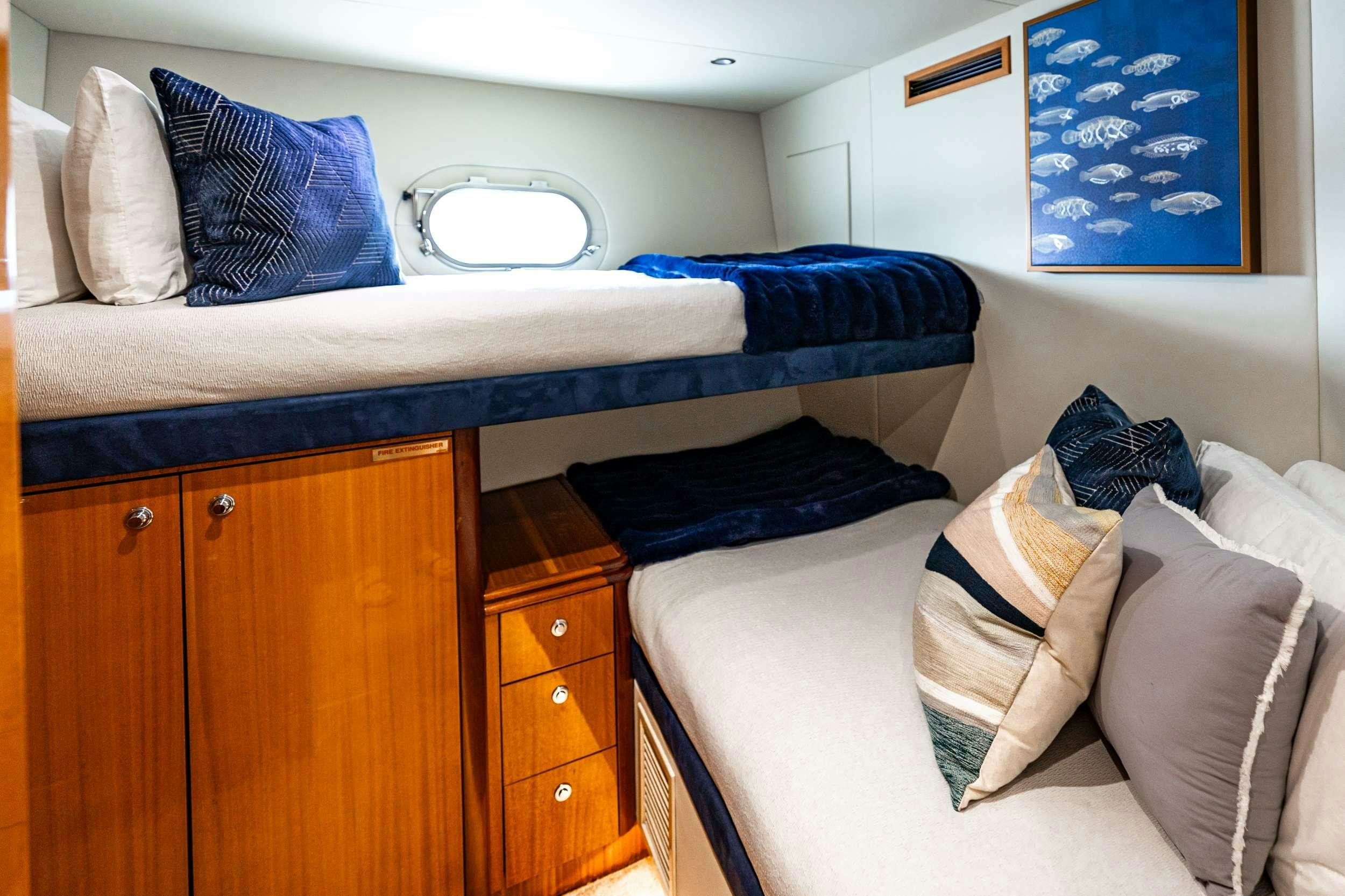 a bed with a blue pillow and a white bed aboard INDY Yacht for Charter