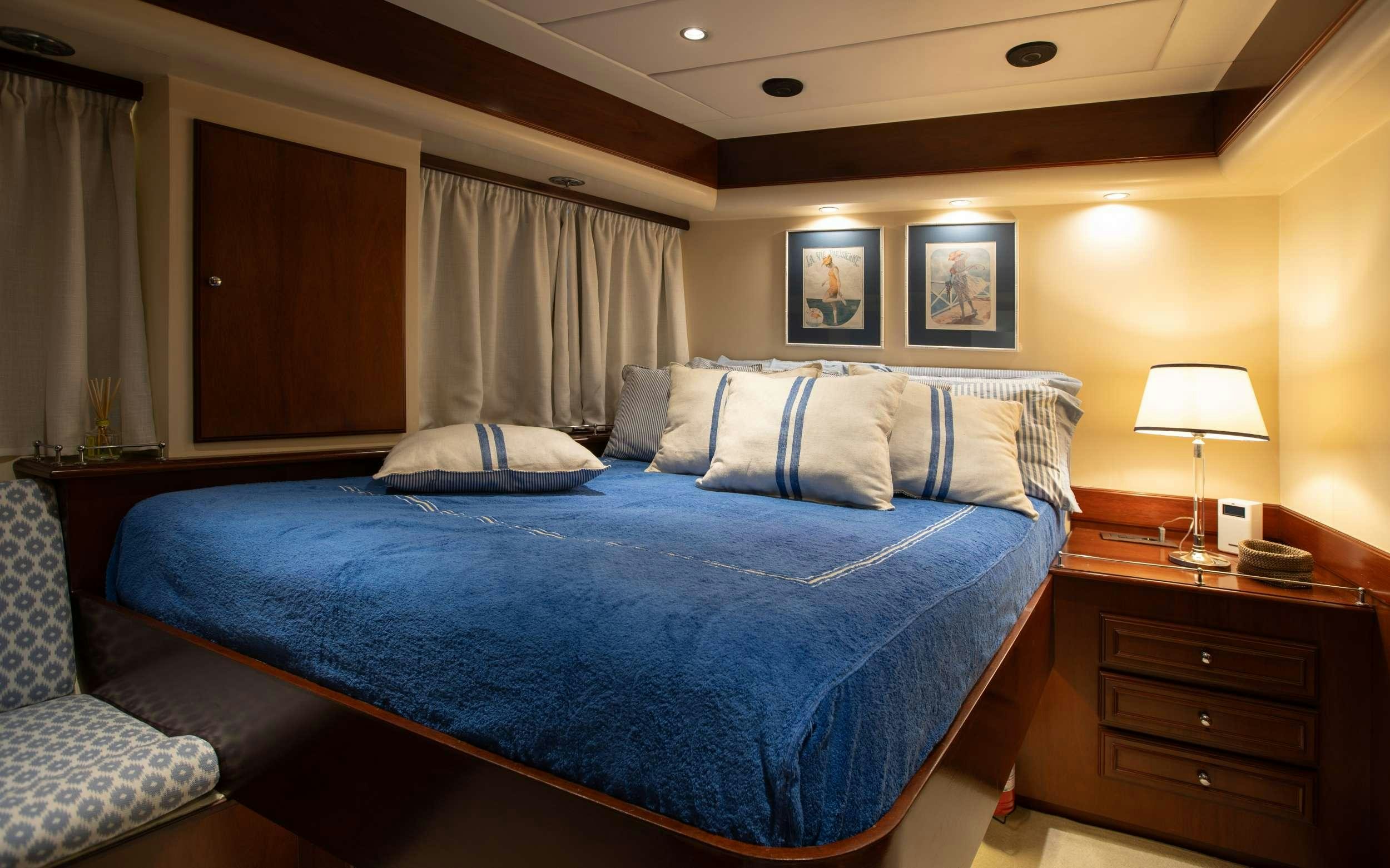 a bed with blue sheets aboard LIBERTY OF LONDON Yacht for Charter