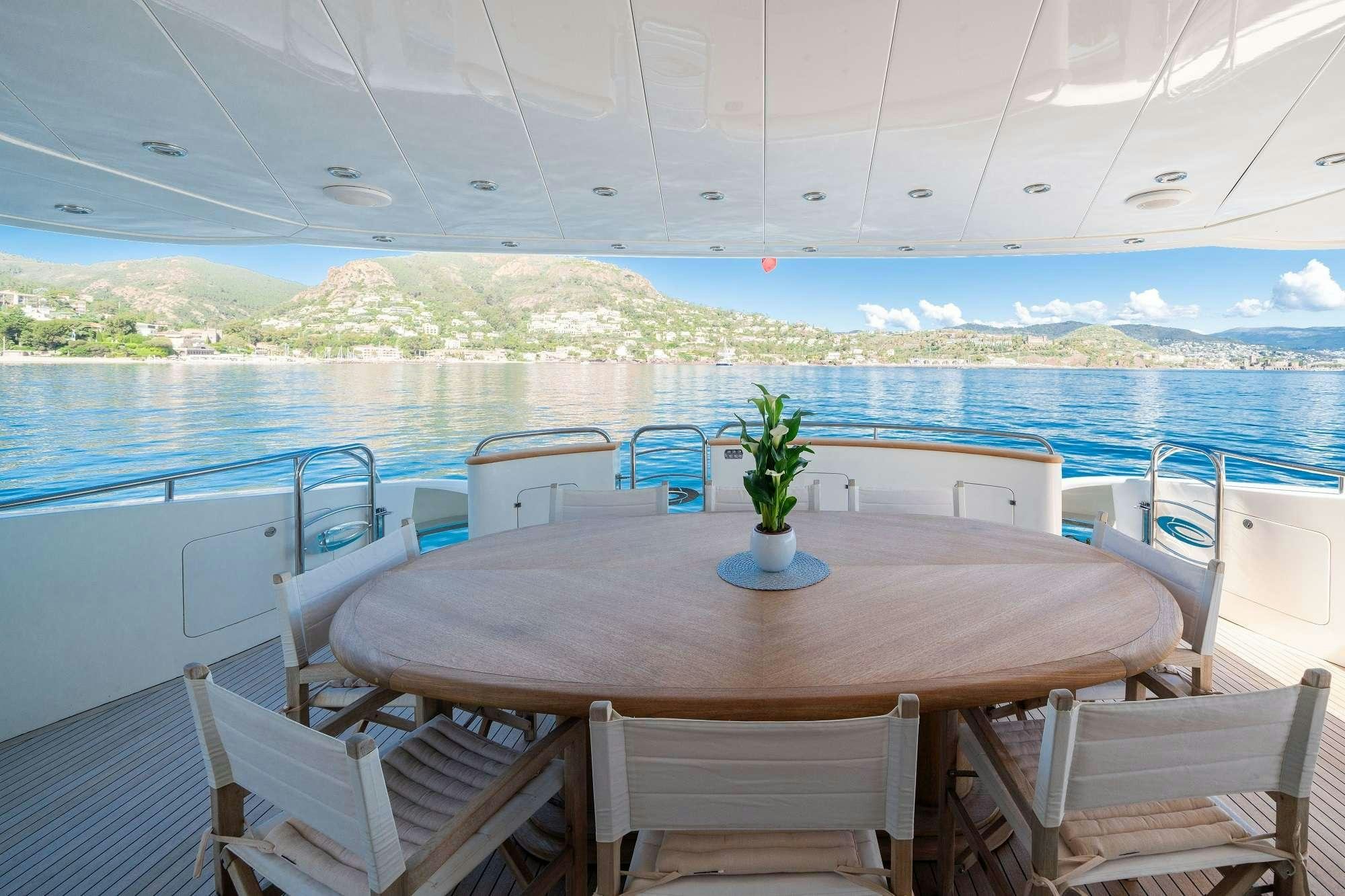 a table and chairs on a deck overlooking a body of water aboard BEIJA FLORE Yacht for Charter